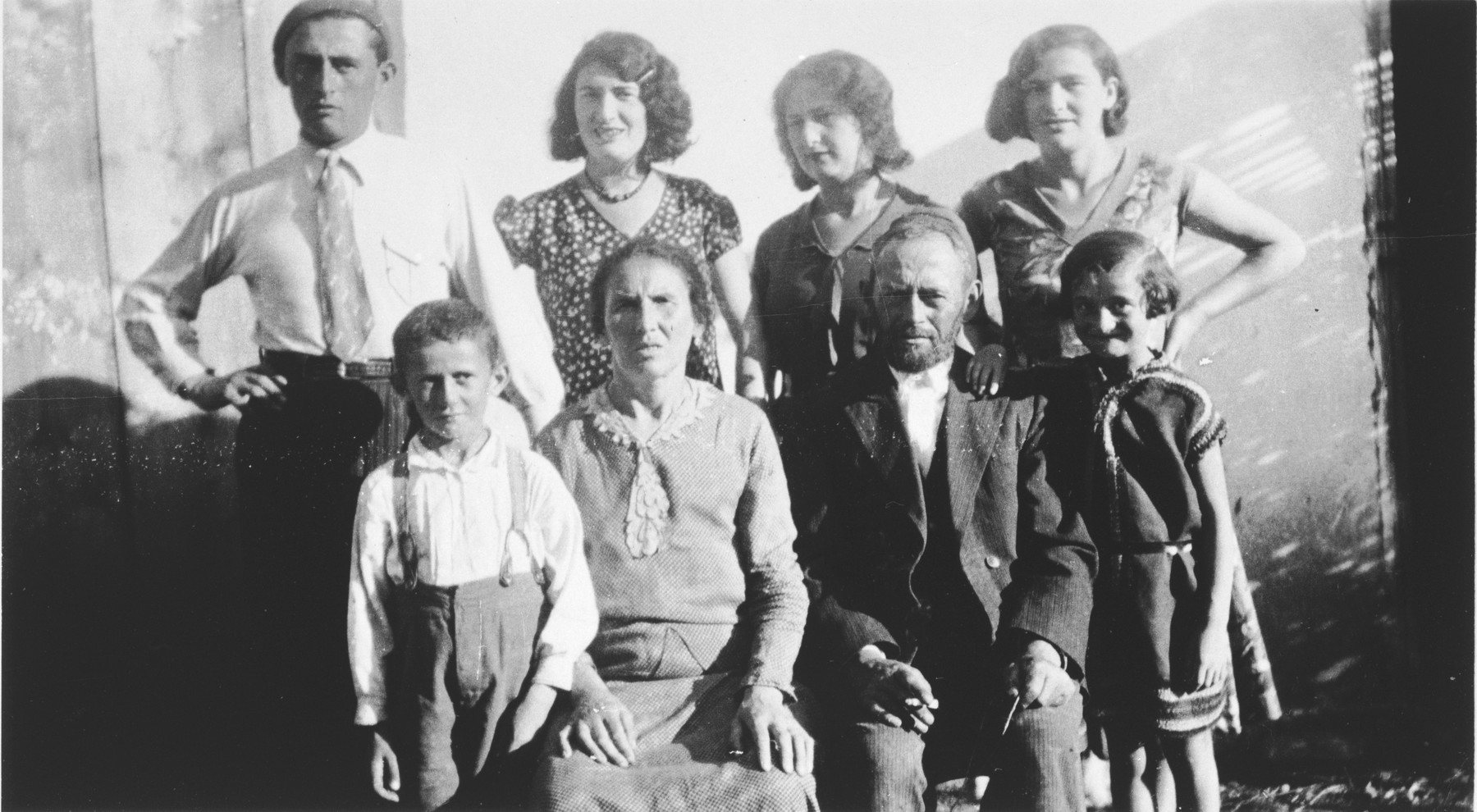 Rivka and Meshilem Frisch pose with their children outside their home in a small shtetl.

Standing from left to right are Yisroel, Fridjeh, Ruzie and Peshe.  Sitting are Dudie, Rivka, Meshilem and Mancha.  Only Fridjeh survived.