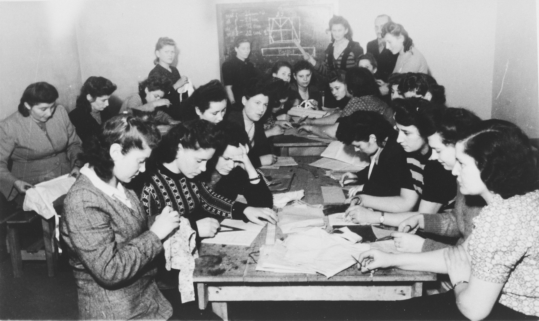 Women do hand sewing in an ORT vocational school in the Zeilsheim displaced persons' camp.

Among those pictured is Fayga Galas, on the left with her hand raised.