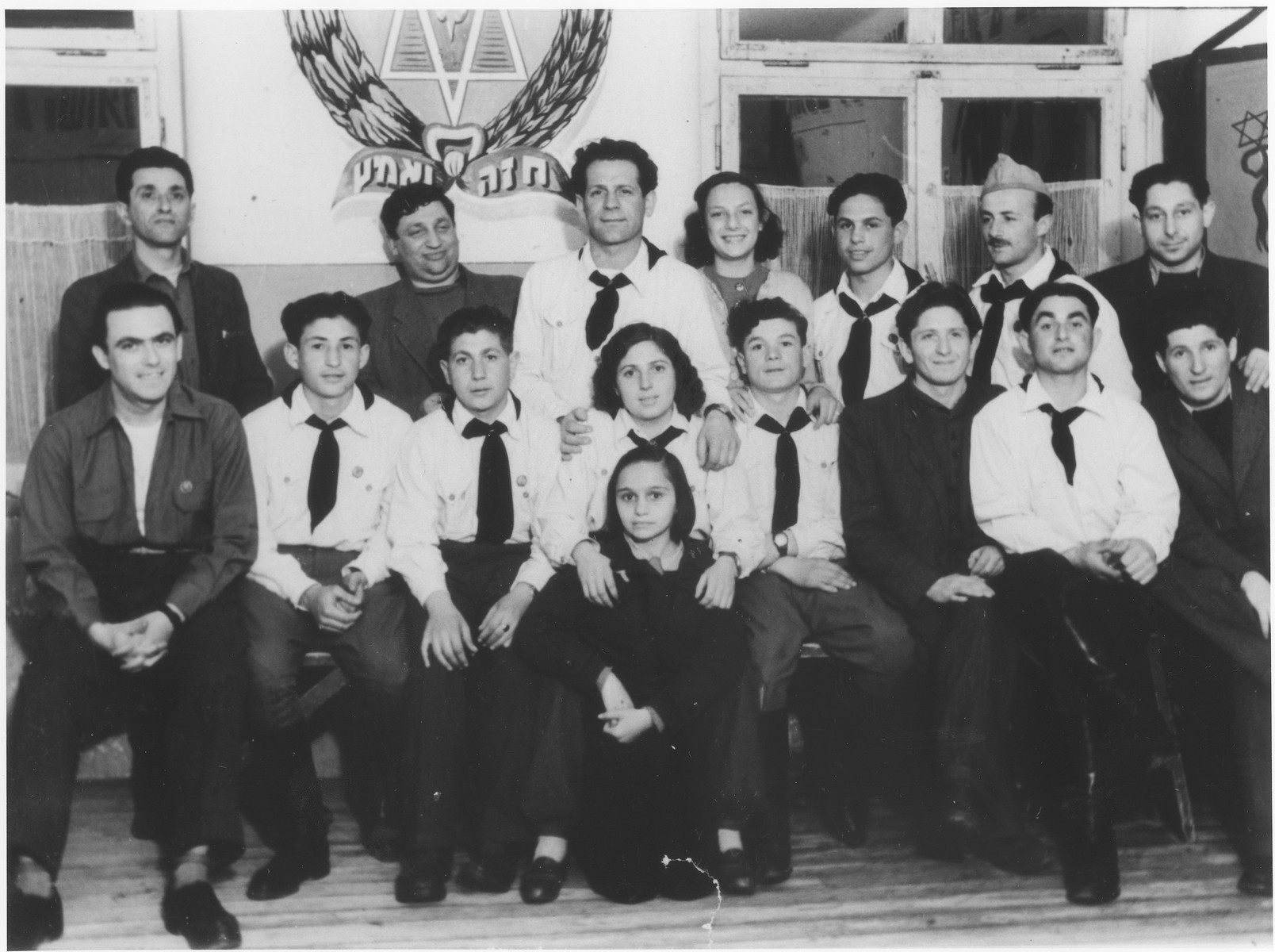 Group portrait of Jewish scouts in the Wetzlar displaced persons camp.  

On the wall is the scout emblem with the Hebrew motto, "Be strong and brave".
