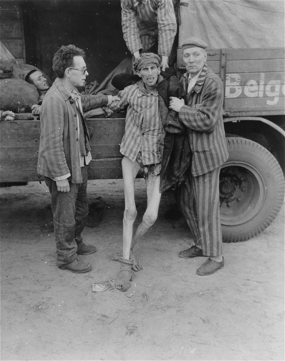 An emaciated survivor is helped into a truck that will transport him from the Woebbelin concentration camp to an American field hospital.