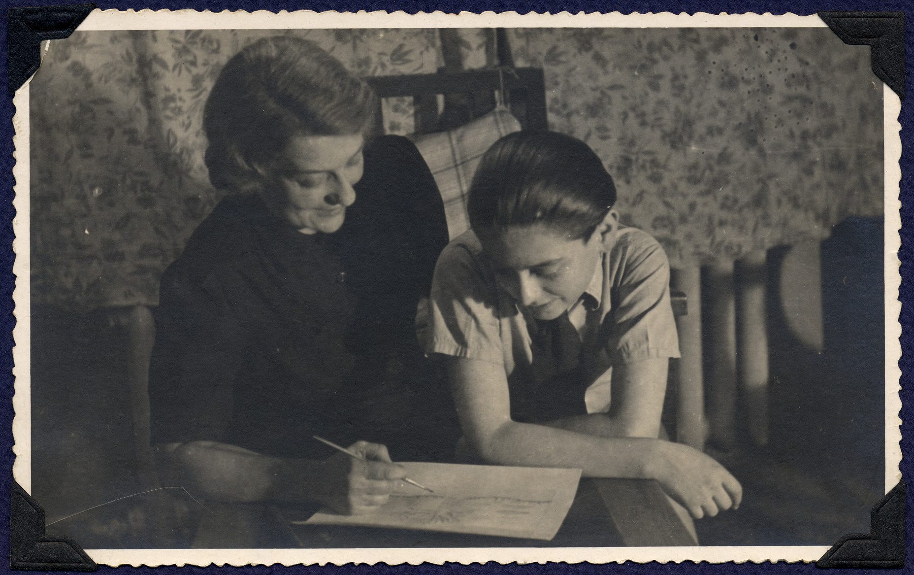 A mother and son, both survivors of Theresienstadt, study a document in their apartment in postwar Prague.

Pictured are Margaret and Michael Grunbaum.