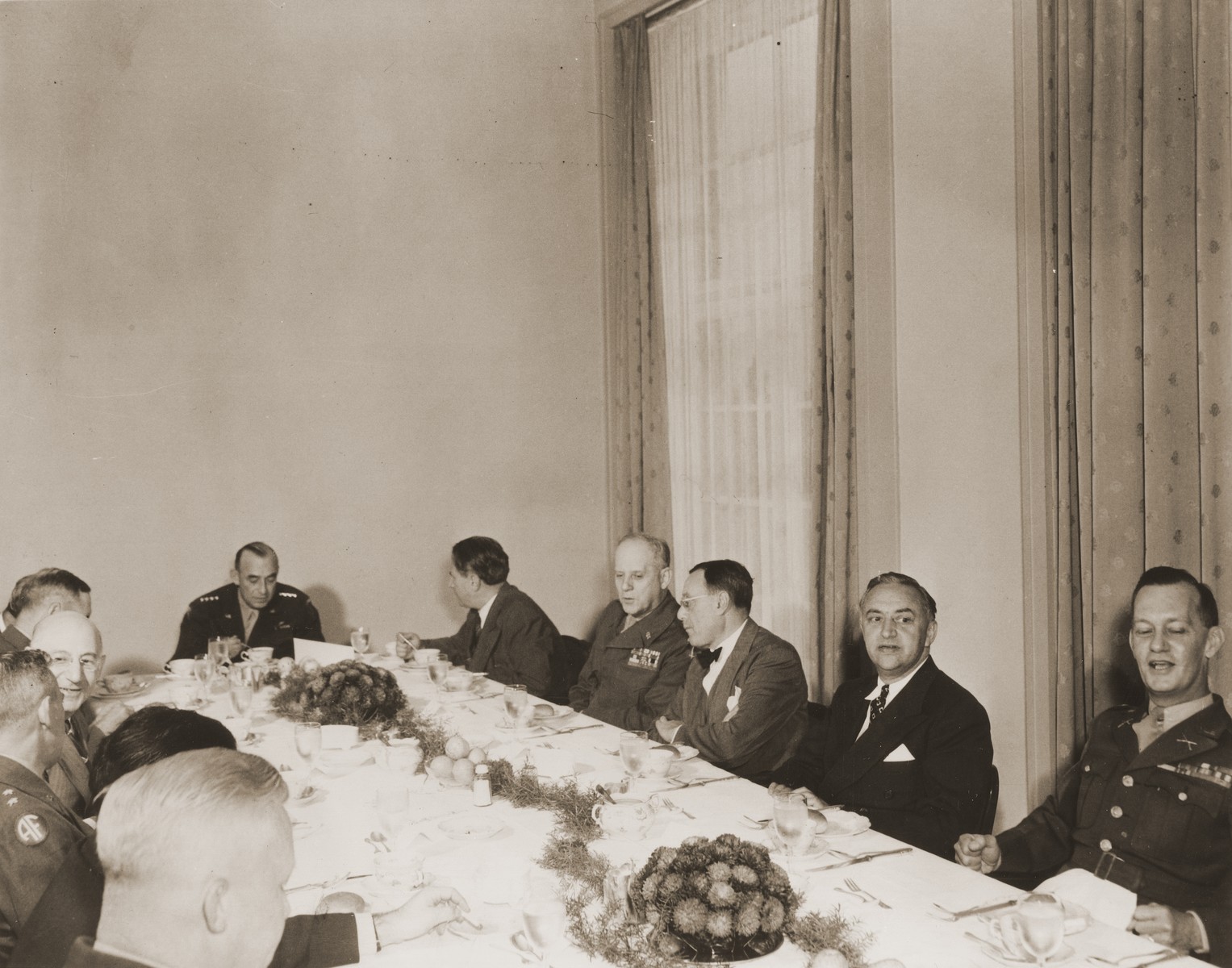 Visiting American Jewish leaders meet over dinner with the commanders of the American army of occupation in Germany.  The meeting took place at military headquarters located in the former I.G. Farben facility in Frankfurt am Main.

Pictured counter-clockwise from the right are: unknown; Rabbi Phillip Bernstein; Philip Forman; General Clarence Huebner; Nahum Goldmann; General Joseph McNarney; Rabbi Stephen Wise; unknown; Jacob Blaustein; unknown; unknown; and Colonel George Scithers.