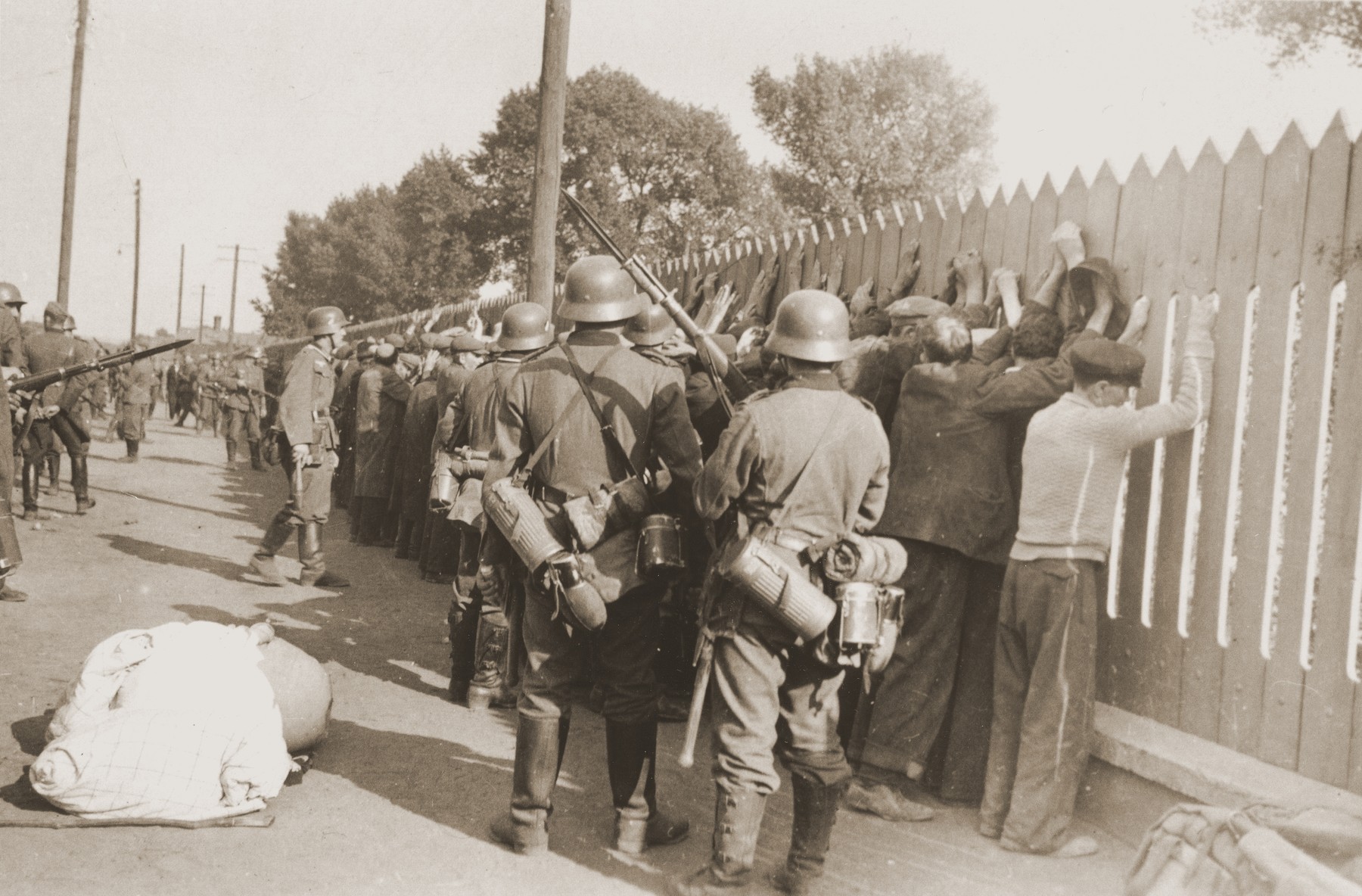 German soldiers round-up a group of Jewish men and line them up against a picket fence in Czestochowa.

One photograph from an album belonging to a member of a Wehrmacht machine gunners' unit, which was found after the war by Lorenzo Hawkins (the donor's grandfather), an American serviceman in Company B, 56th Armored Engineer Battalion.