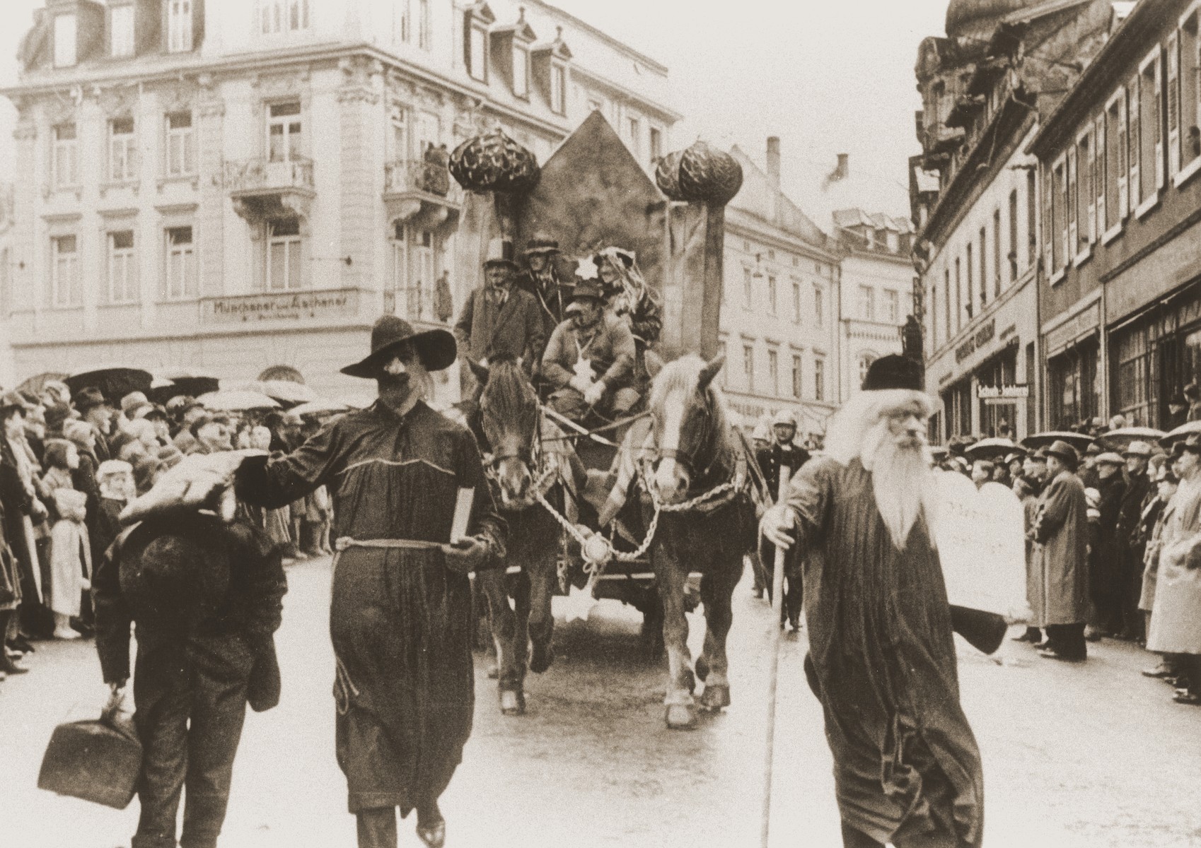 A troupe of actors in a carnival parade parodies Jewish life in Germany.  The float features a mock-up of a burning synagogue.