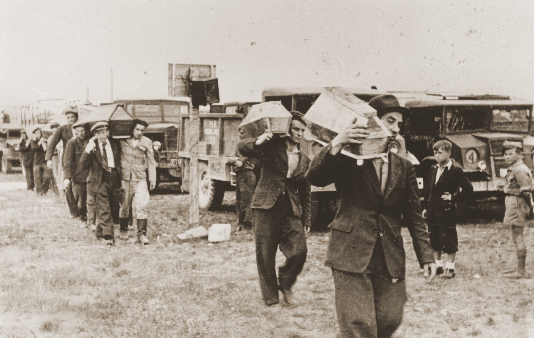 Pallbearers carrying the the victims of the Kielce pogrom, transport the coffins from trucks to the burial site in the Jewish cemetery.