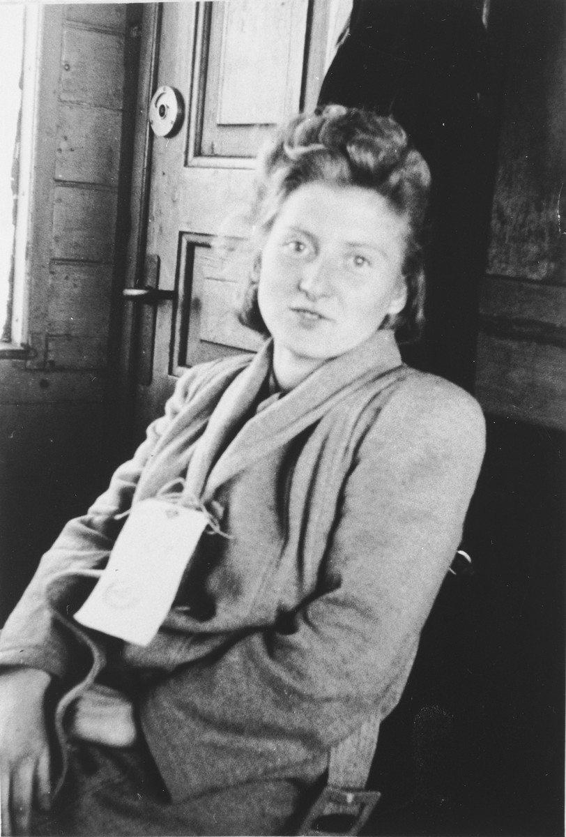 Eva (Mrowka) Sterner sits in a train station wearing a name tag while awaiting transport to Canada.