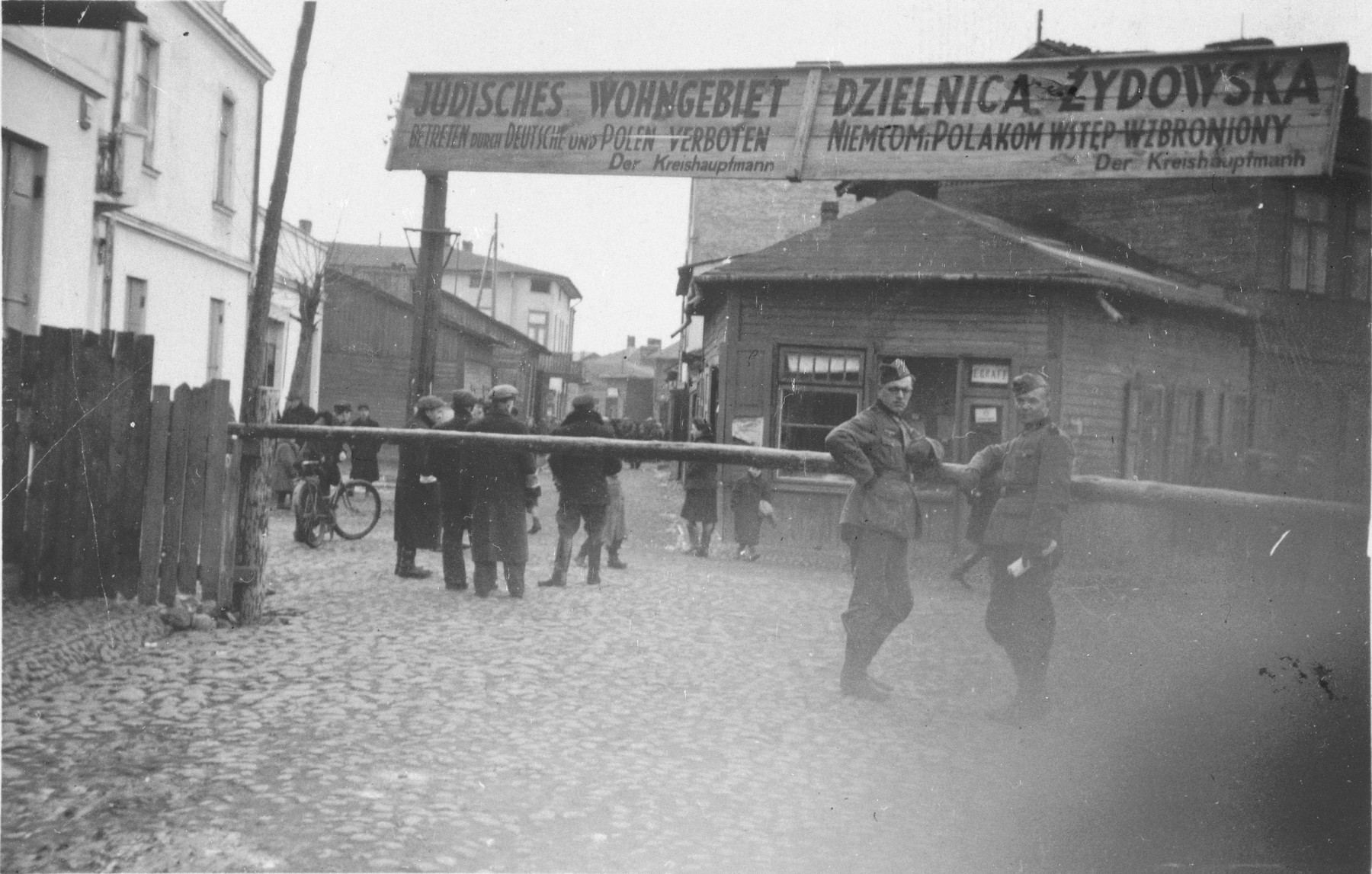 Two German soldiers stand at the entrance to the Otwock ghetto at  ul. Andriollego Michala.

The sign in Polish and German states that entrance to the Jewish quarter is forbidden to Germans and Poles.