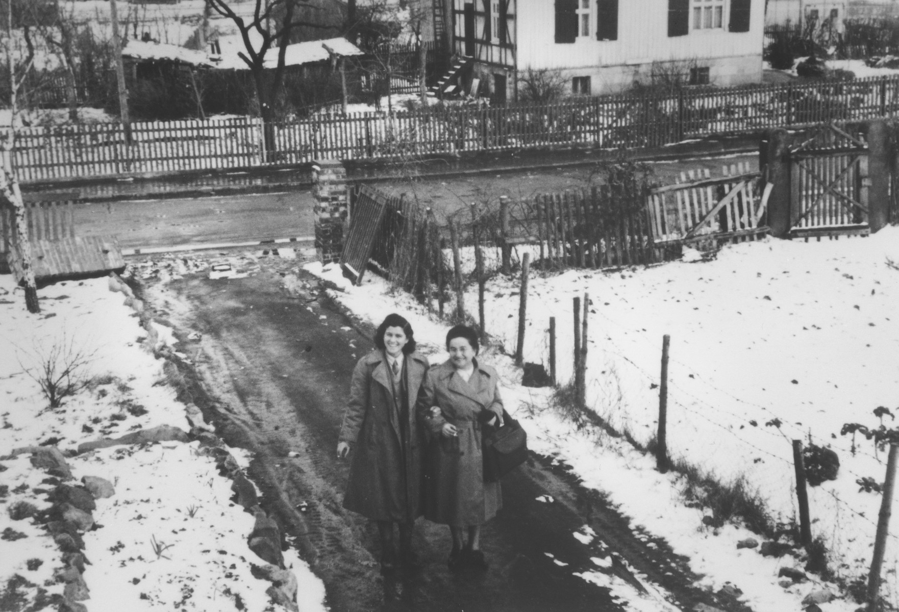 Two Jewish female relief workers walk along a path in the Herzog displaced persons camp.

Pictured on the left is Miriam, a sabra sent by the Jewish Agency for Palestine to teach Hebrew to Jewish DPs.  On the right is Mrs. Greenberg from the American Jewish Joint Distribution Committee in New York.