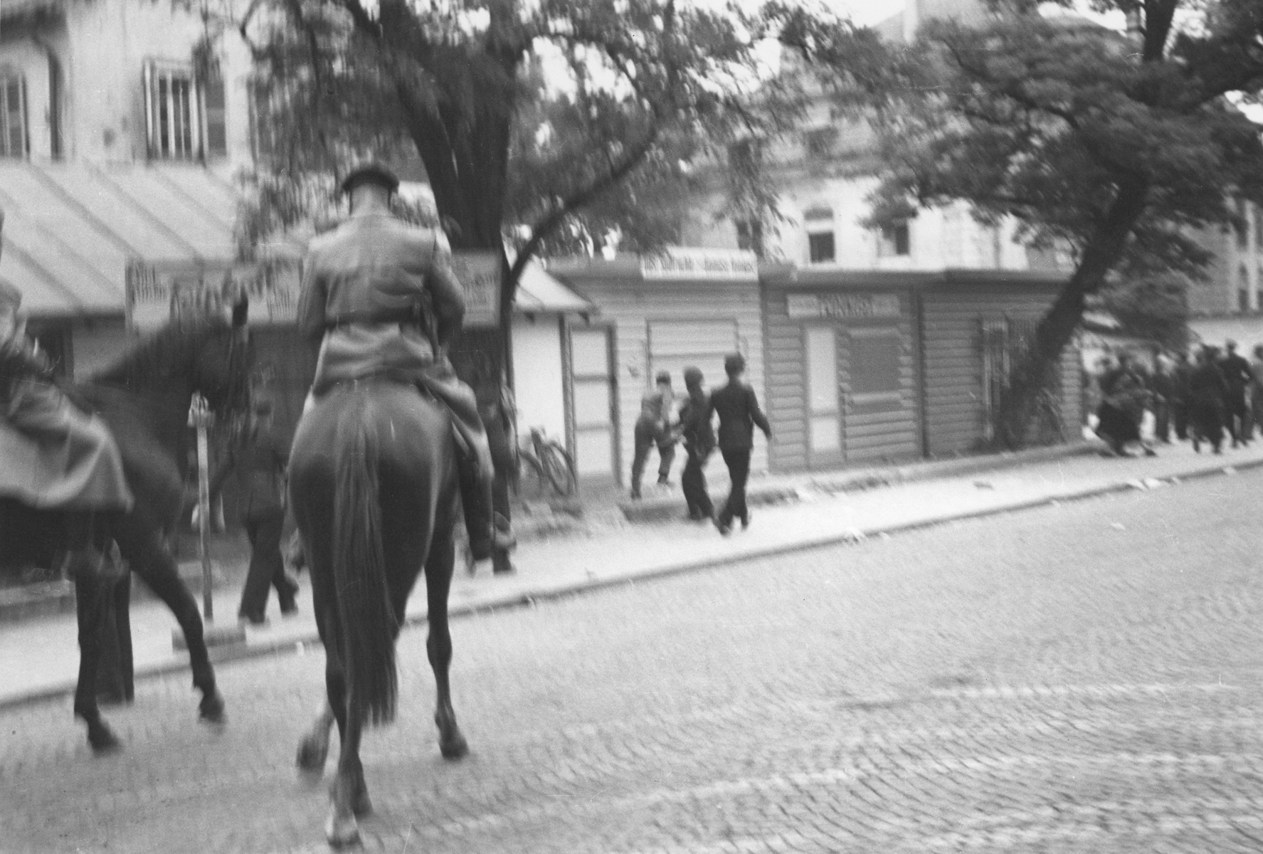 German police on horseback conduct a raid to suppress Jewish black market activity on the Moehlstrasse in Munich.