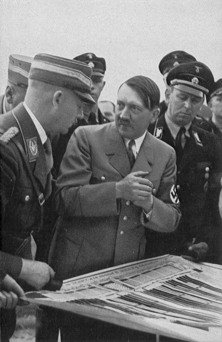 Adolf Hitler discusses plans for the parade at Reichsparteitag (Reich Party Day) ceremonies in Nuremberg.

Pictured on the left is Viktor Lutze and on the right is Julius Schaub.