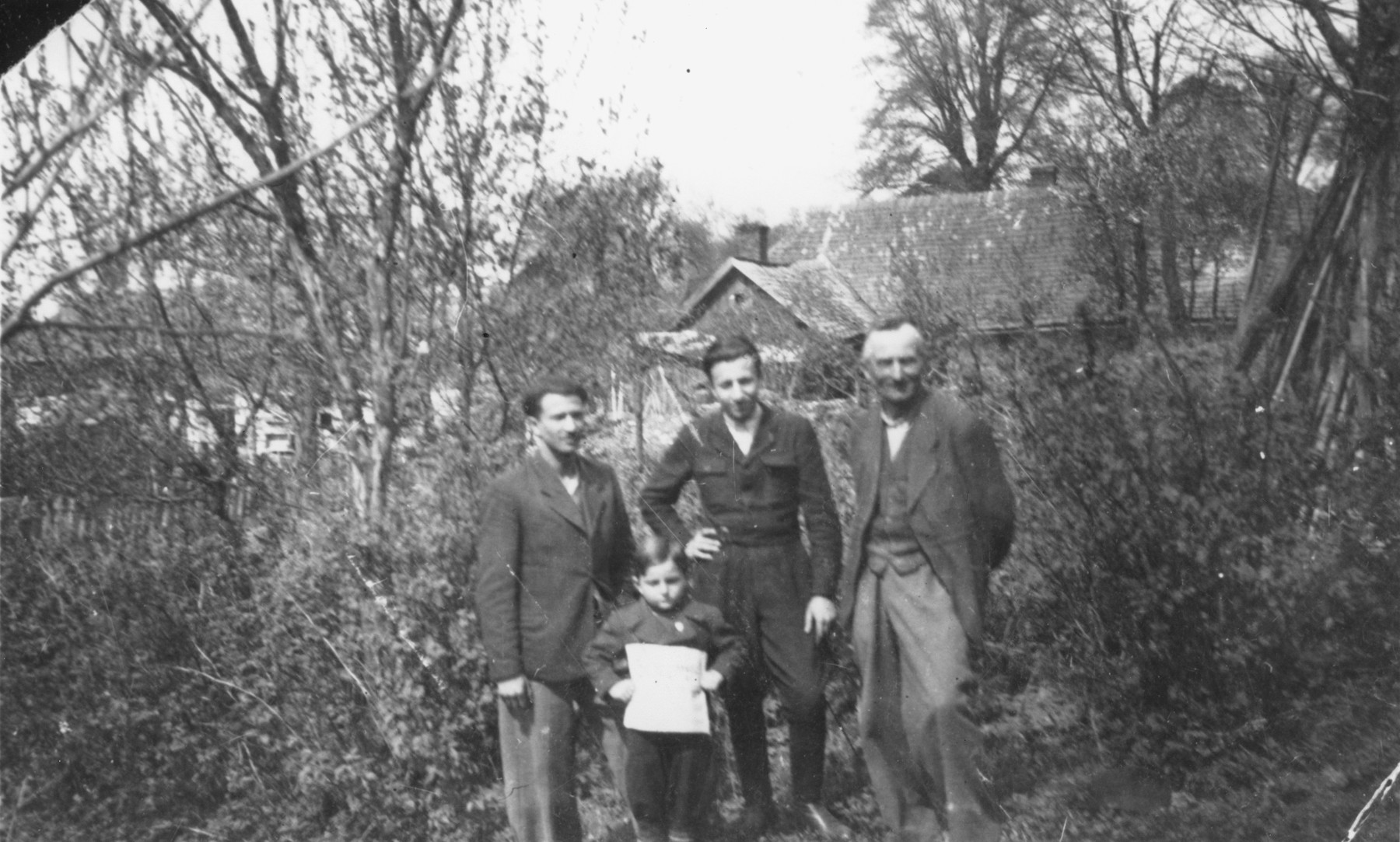 Nathan Berliner (center), a Jewish survivor, who during the German occupation of Poland had lived in hiding in Lancut, poses with his rescuer, Mr. Spiwak (right), who allowed him to live in his barn.

Also pictured is Beniek Kleinminc (left) and Itzhak Gerstein (in front).