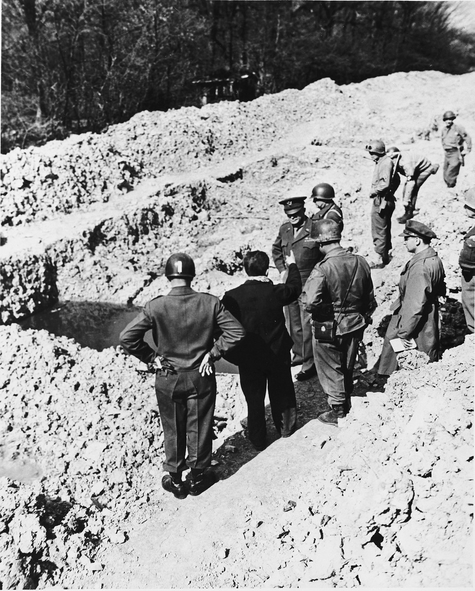 An Austrian-Jewish survivor shows high-ranking U.S. Army officers a mass grave in the newly liberated Ohrdruf concentration camp.

Among those pictured are Generals Dwight D. Eisenhower, George Patton, Omar Bradley and Manton Eddy.  Also pictured is Jules Grad, correspondent for the U.S. Army newspaper, "Stars and Stripes".  Also pictured is Ignaz Feldmann (back to camera, wearing a dark coat and a scarf) . He was a survivor of  Westerbork, Terezin, Auschwitz, and Ohrdruf camps.   He was also a player on the famed Hakoah Vienna soccer teams of the 1920s and 30s.