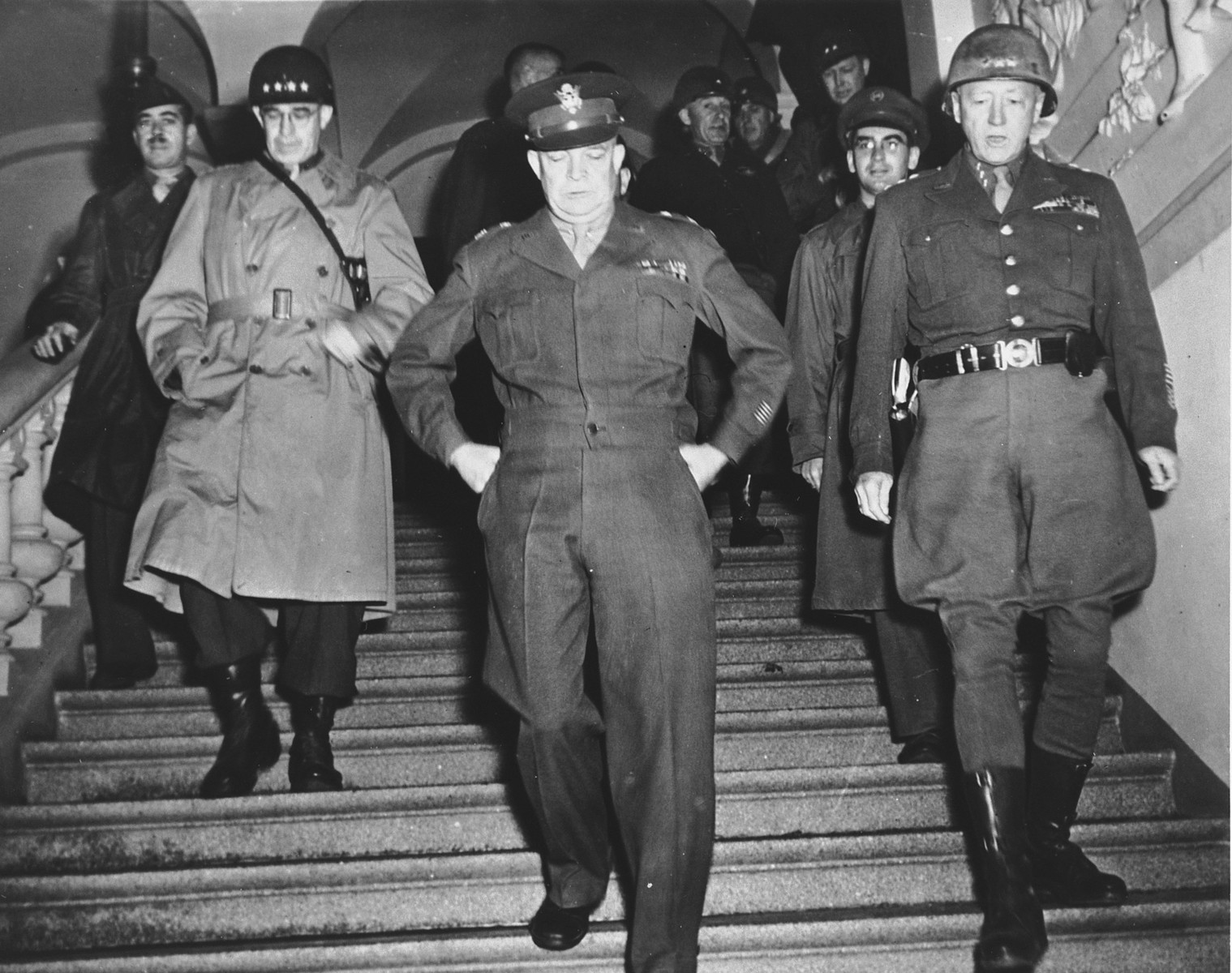 High-ranking U.S. Army officers descend the stairs at an unidentified army headquarters in Europe.

Pictured from left to right are: Lt. Gen. Omar K. Bradley, Gen. Dwight D. Eisenhower, and Lt. Gen. George S. Patton.  Sgt. Jules Grad, correspondent for the newspaper, "Stars and Stripes", walks behind Patton.