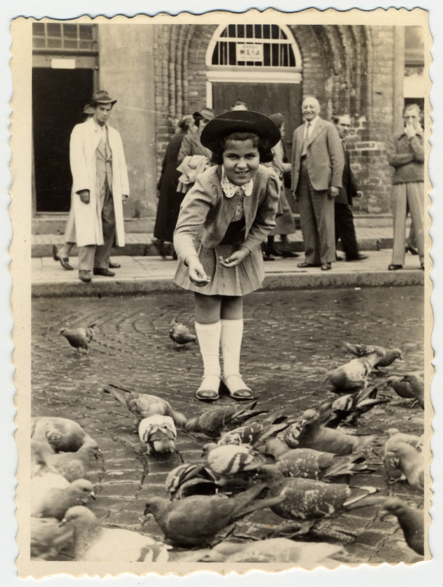 A young girl feeds pigeons in an public square in Warsaw.

Pictured is Inka Gerson.