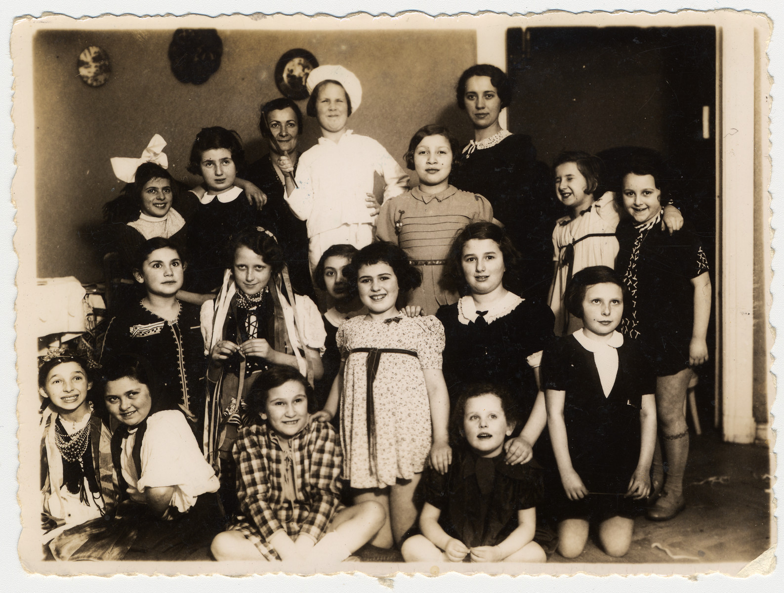 A group Polish Jewish girls, many of whom are wearing costumes, attend the 10th birthday party of Inka Gerson.

Among those pictured is Inka Gerson.  Her cousin, Janka Stillerman (later Yael Star) is wearing a cook's outfit.  The costumes with the ribbons and beads are a national Polish costume from the Krakow region.