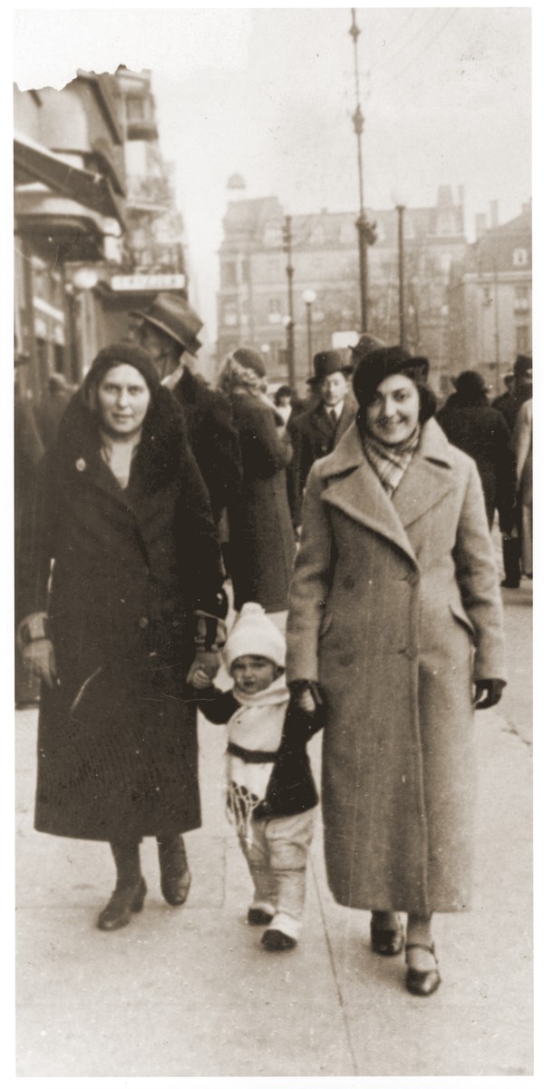 Salusia Goldblum walks between her mother Tola and aunt Nacha Broda on a street in Katowice.