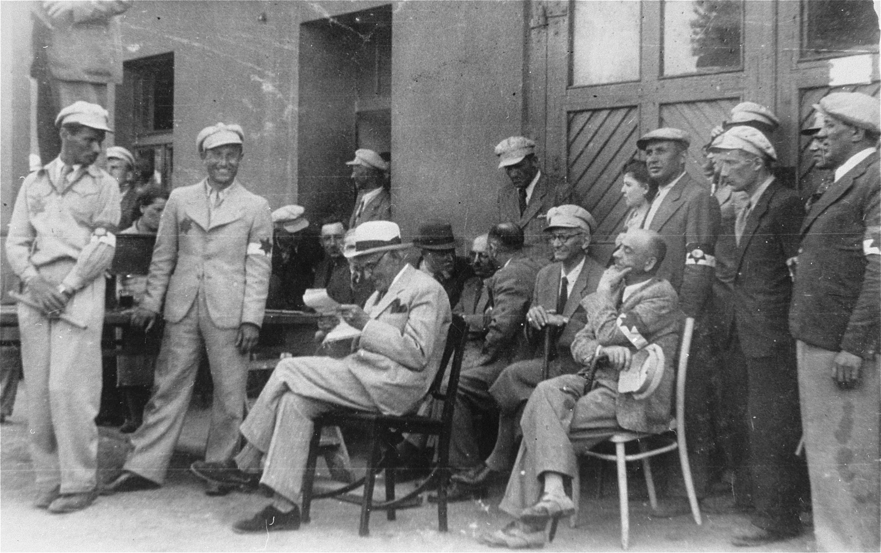 Mordechai Chaim Rumkowski (seated in the center), attends an event with members of the Jewish police and Sonderkommando.

Also pictured is Leon Rozenblat (seated at the right, holding his cap).