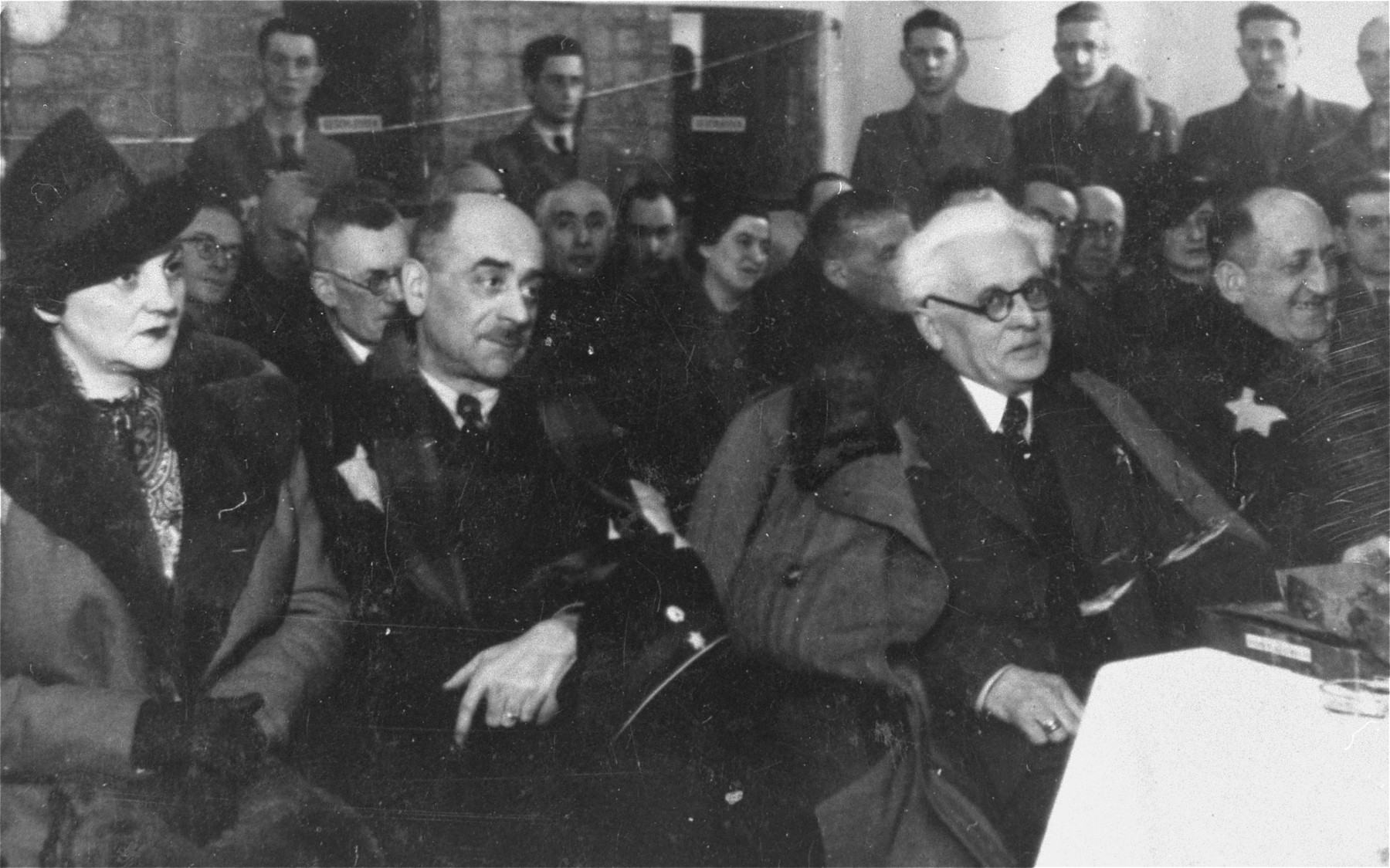 Jewish council chairman Mordechai Chaim Rumkowski (center, left), attends a ceremony in the Lodz ghetto at which he was given a presentation album.

Pictured in the front row from left to right are: Helena Rumkowska, Leon Rozenblat, Mordechai Chaim Rumkowski and Dr. Leon Szykier.