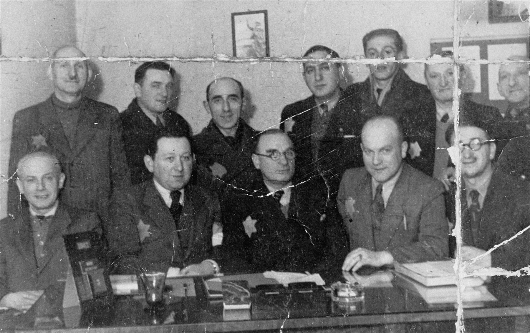 Group portrait of members of the Jewish council in an office in the Lodz ghetto.

Among those pictured are Zygmunt Reingold, director of food supply (seated second from the left) and Max Szczesliwy, co-director (seated in the middle).