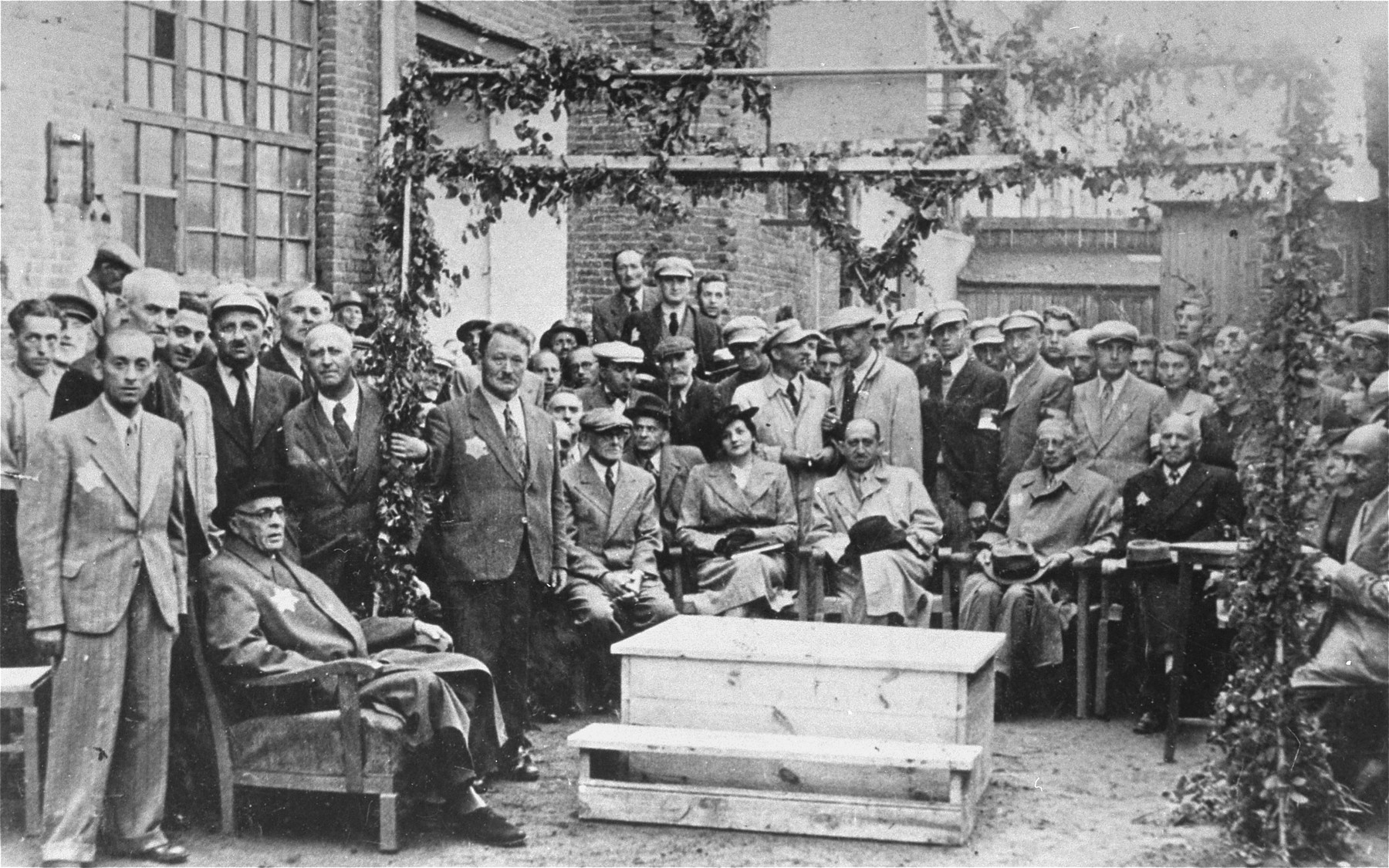 Mordechai Chaim Rumkowski (seated at the left) attends a public ceremony in the Lodz ghetto.

Among those pictured are: Baruch Praszker (standing behind Rumkowski), Stefania Dawidowicz (seated in the center, wearing a hat), Dr. Leon Szykier (seated next to Dawidowicz), Jozef Rumkowski (seated next to Szykier), Leon Rozenblat (far right).  All others are members of the ghetto police.