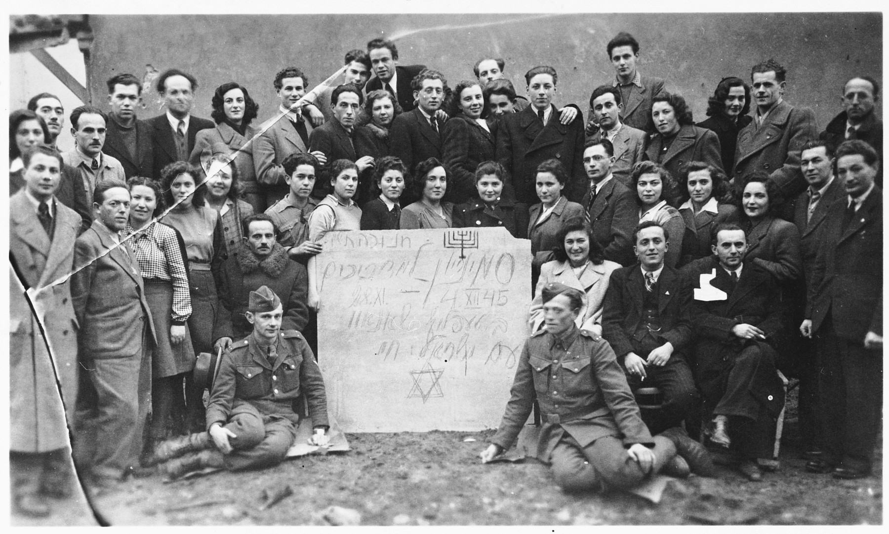 Group portrait of Jewish DP youth posing with a sign at a seminar of the Dror-Hehalutz Zionist youth movement in Czechoslovakia.

Among those pictured is Rahel Berger (second row from the front, fifth from the right).