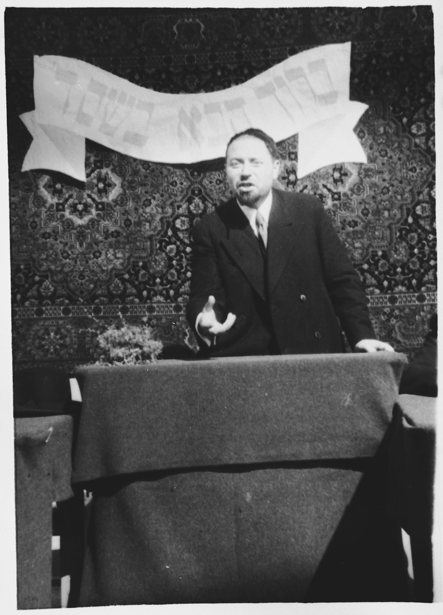 Rabbi Riccardo Pacifici addresses the internees in the Ferramonti camp.

The banner behind him reads "Blessed be your coming in the name of the Lord."