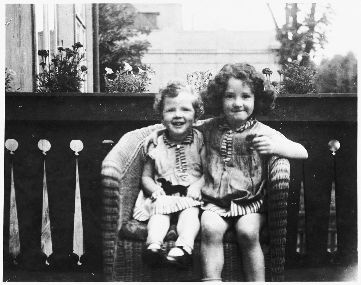 Shulamit and Gitta Posner share a wicker chair on the porch of their home in Kiel, Germany.