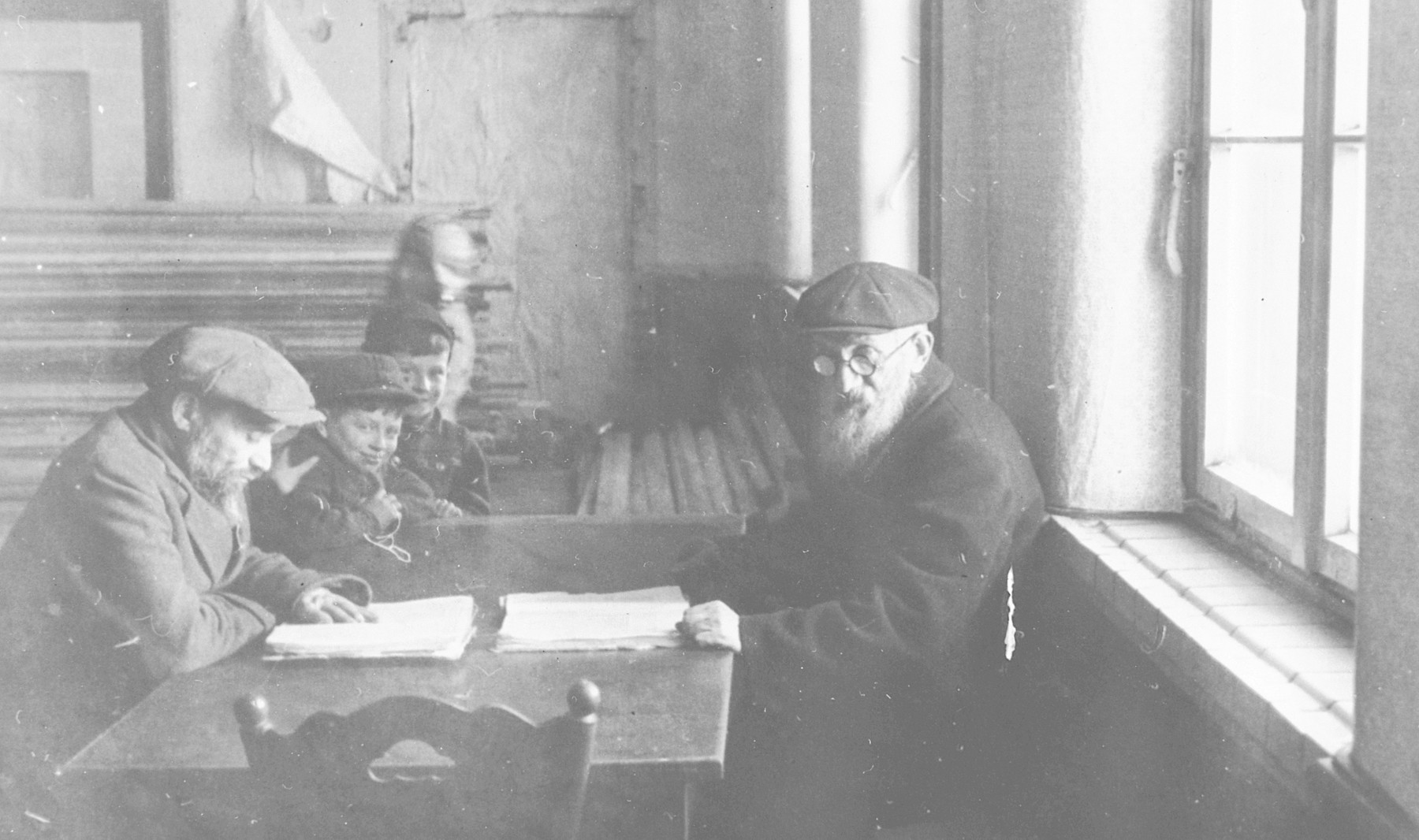 Jewish men with onlooking young boys read at the Wetzlar displacement camp.

The original caption reads, "a familiar scene brought back memories."