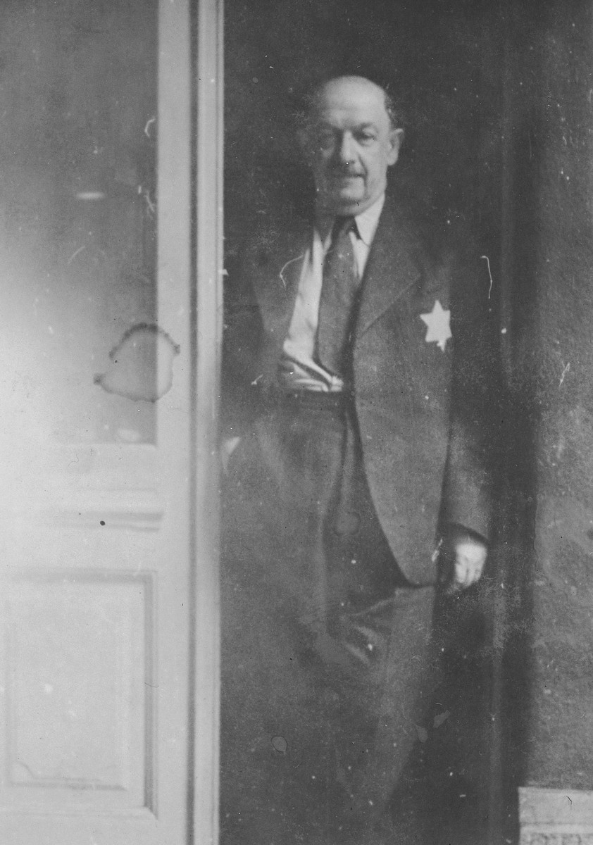 A Hungarian Jewish man, stands in a doorway wearing a yellow star.

Pictured is Marcus Trebitsch, the donor's uncle.  He had served as the head of the Chevra Kaddisha (burial society) for the Neologue community.  He survived the war.