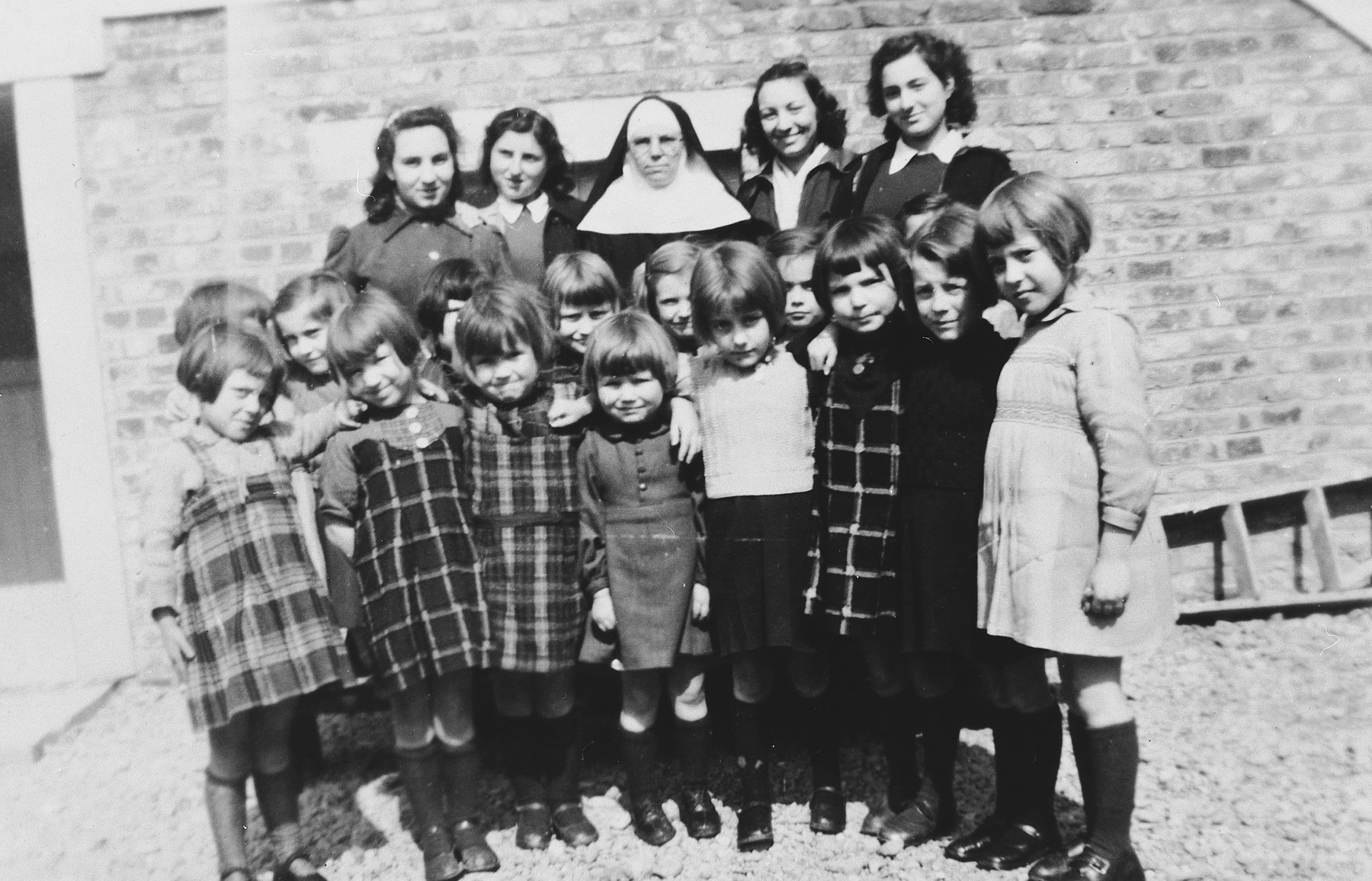 Two Jewish sisters pose with the nun who had hidden them and a group of Belgian children in the Couvent de la Misericorde in Louvain.

Pictured in the back row are Cecile and Anny Rojer and Sister Clotilde.