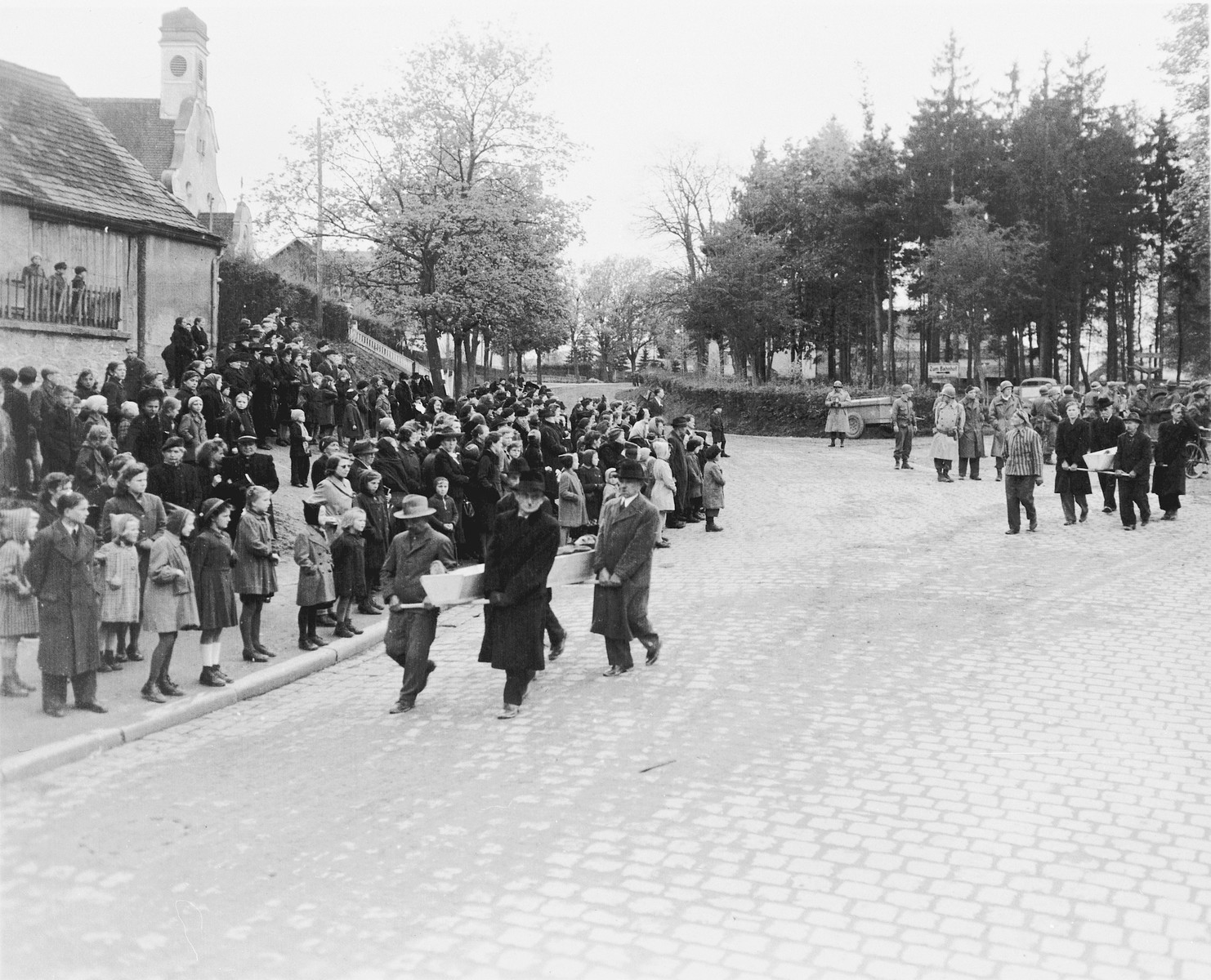 The townspeople of Neunburg vom Wald line the streets and watch as their fellow townspeople transport corpses found in the nearby forest to the town cemetery for proper burial.  

The victims were Polish, Hungarian, and Russian Jews shot near Neunburg while on a death march from Flossenbuerg.