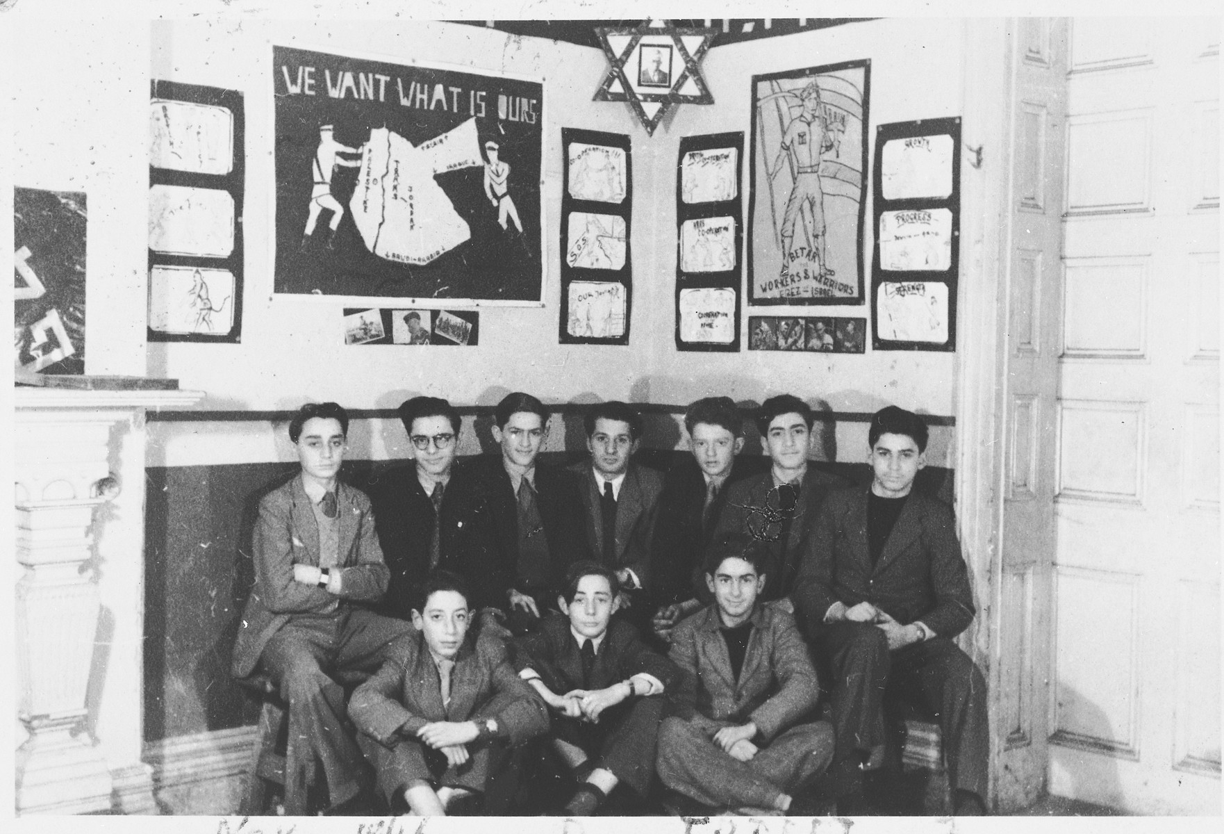 Members of the Revisionist Zionist youth group in Shanghai pose in front of a wall of posters and photographs.