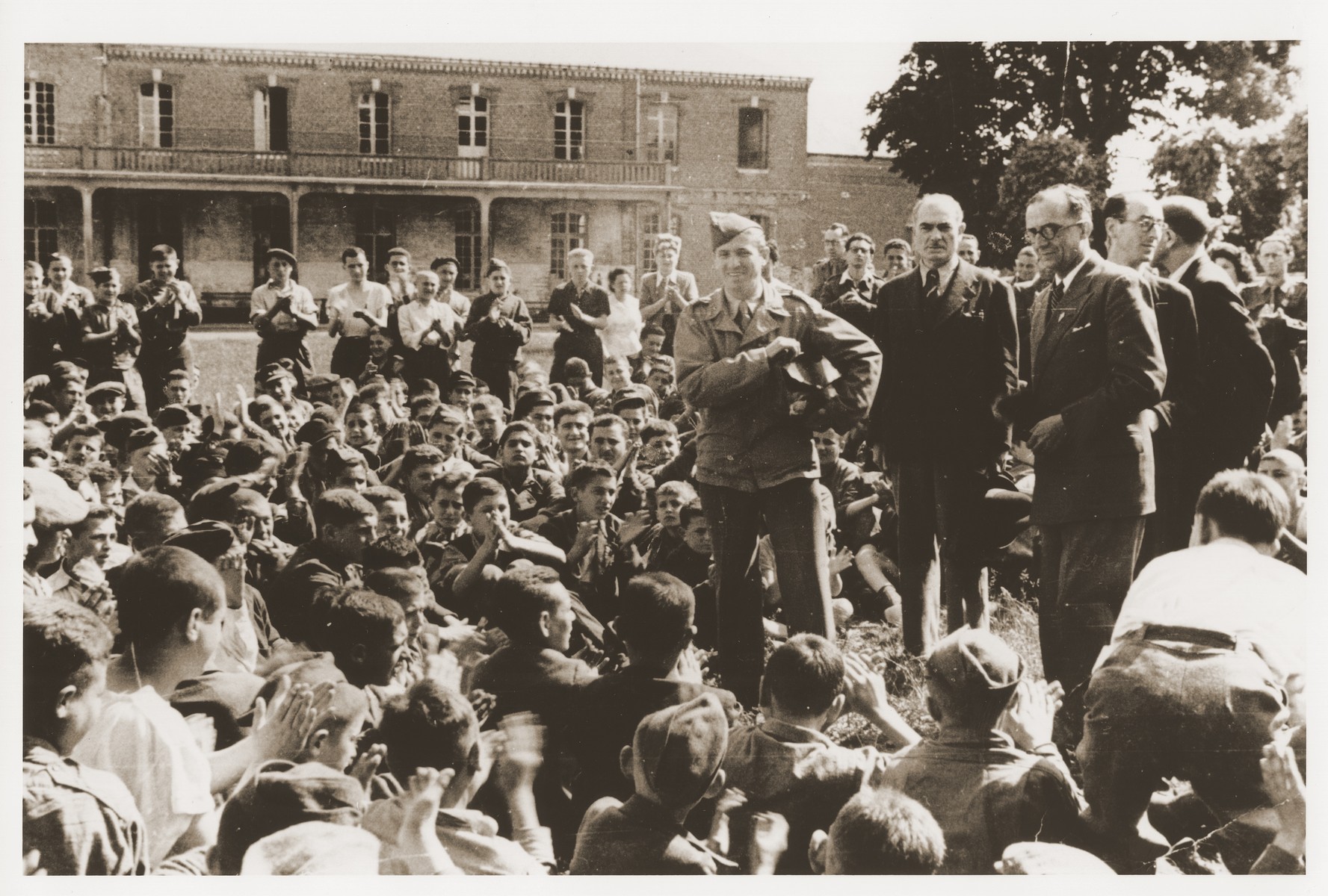 Jewish youth who were members of the Buchenwald children's transport listen to Colonel Rozen and representatives of the OSE at an outdoor meeting at the Ecouis children's home.