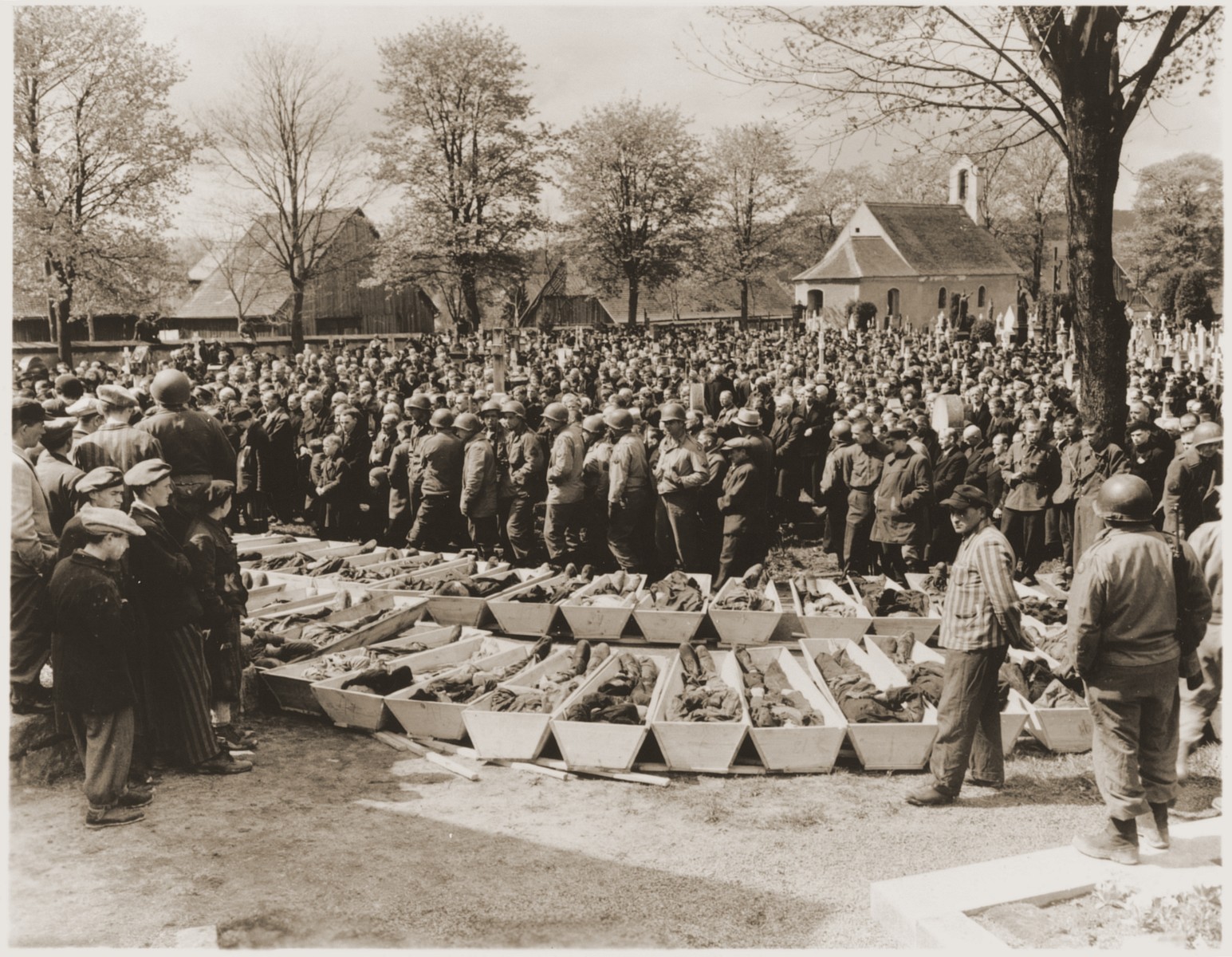U.S. troops and German civilians from Neunburg vorm Wald attend a funeral service for Polish, Hungarian, and Russian Jews found in the forest near their town.  The victims were shot by the SS while on a death march from Flossenbuerg.