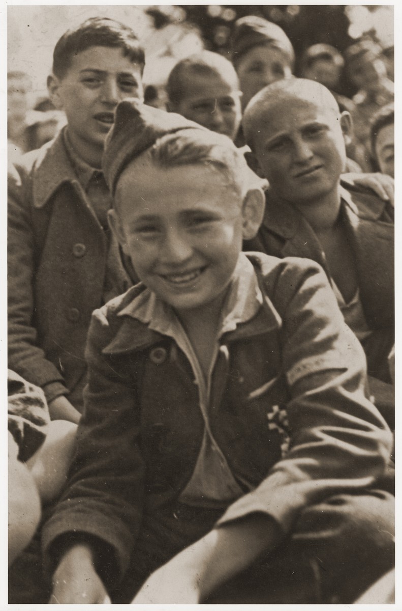 Jakub Finkelstajn sits among the members of the Buchenwald children's transport at an outdoor gathering on the grounds of the Ecouis children's home soon after their arrival.

A French military decoration is pinned to the pocket of his uniform.