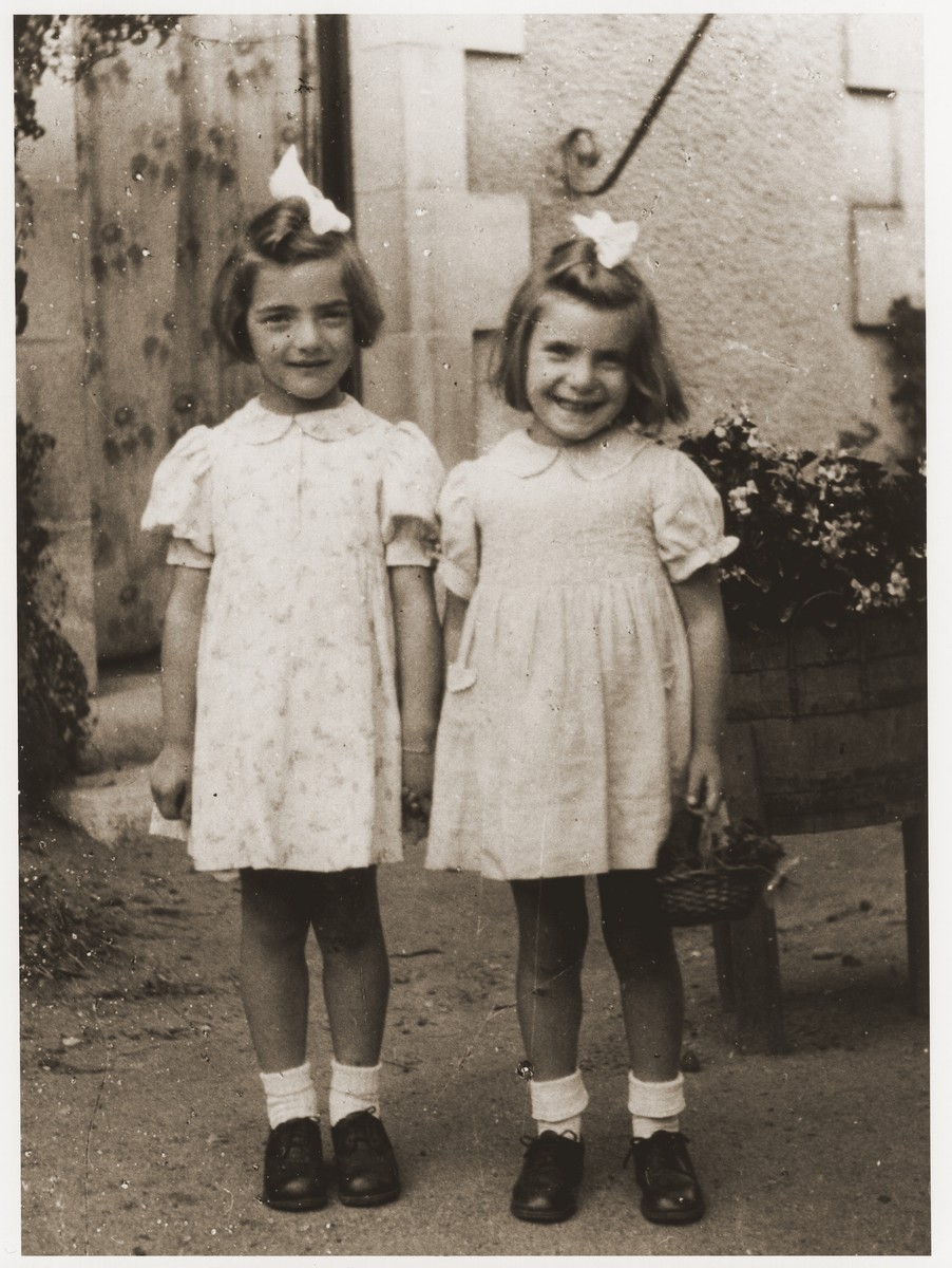 Two young Jewish sisters, Felice and Beate Zimmern, pose outside the home of Gaston and Juliette Patoux, the French couple who had sheltered them during the German occupation.  

The girls, who have moved to the OSE children's home at Taverny after the war, are paying a visit to their rescuers.