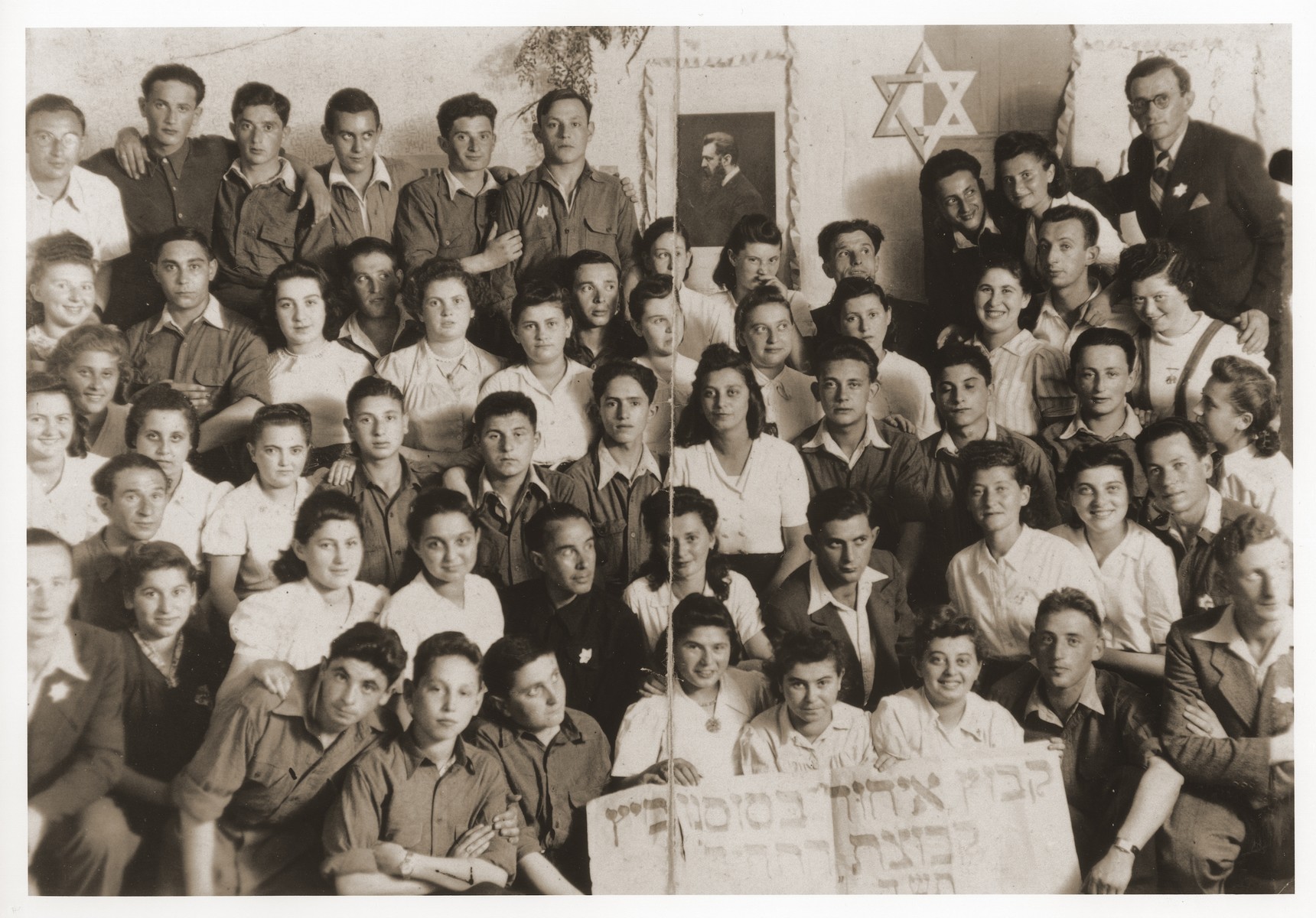 Group portrait of the members of the Kibbutz Ichud hachshara in Sosnowiec.

Szaja Aron Knobler (now Alex Knobler) is the son of Moszek and Jocheta Knobler.  He was born in 1921 in Bedzin, Poland.  Szaja had three older sisters, Ita, Esther and Leah.  In 1931 the family moved to Chorzow near the German border.  There Szaja became active in the Akiba Zionist youth movement.  In 1938 he joined the Akiba hachshara [agricultural training farm] in Bielsko and made plans to immigrate to Palestine.  His plans were thwarted, however, by the start of World War II.  In the first months of the war Szaja fled to the Soviet sector of Poland, where he explored possible exit routes to Palestine via Romania for the nascent Zionist underground.  During a visit home in 1940 Szaja was caught up in the forced resettlement of his family to the Sosnowiec ghetto.  From Sosnowiec Szaja was deported to the Blechhammer labor camp, where he remained until the camp was evacuated in January 1945.  During the forced march out of the camp Szaja ran away with two friends.  German guards shot and killed his friends but Szaja escaped.  Posing as a Polish laborer, Szaja found refuge with a German farmer in Gleiwitz until liberation.  After the war Szaja, who was the sole survivor of his immediate family, took a leading role in the setting up of Zionist collectives in Poland.  He also was active in the Bricha and Aliyah Bet [illegal immigration to Palestine] movement.  This activity led to his arrest in Sosnowiec by the NKVD.  Following his release from prison, Szaja left Poland for Germany.  During the summer of 1945 Szaja organized Zionist activities at the Foehrenwald displaced persons camp.  In October he moved on to the Bergen-Belsen DP camp, where he joined a group of 400 would-be immigrants to Palestine.  The group sailed aboard the Tel Hai from Marseilles in March 1946.  When the ship reached Palestine, it was intercepted by the British and its passengers interned for three weeks in Athlit.  Following his release Szaja settled in Kibbutz Masada, but by December 1946 he was back in Germany.  Serving as an emissary for NOHAM (Noar Halutzi Meuchad), a Zionist youth umbrella group, Szaja distributed immigration certificates and organized Youth Aliyah groups in the DP camps.  While working at the Belsen DP camp Szaja met Pola Blicblum, a survivor from Lodz.  They were married in the Landsberg DP camp on July 30, 1947.  Soon after they settled in Palestine.