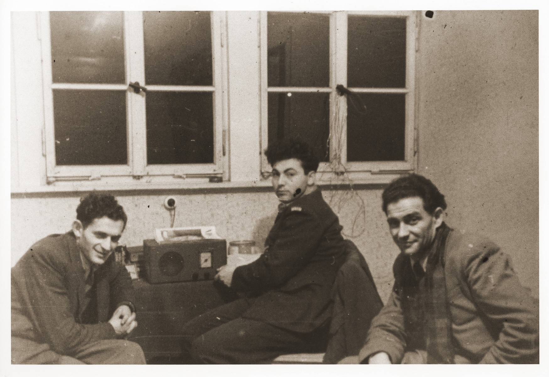 Emissaries from Palestine sent by the Haganah listen to a radio broadcast of the UN partition vote in the Bergen-Belsen displaced persons camp.

Szaja Aron Knobler (now Alex Knobler) is the son of Moszek and Jocheta Knobler.  He was born in 1921 in Bedzin, Poland.  Szaja had three older sisters, Ita, Esther and Leah.  In 1931 the family moved to Chorzow near the German border.  There Szaja became active in the Akiba Zionist youth movement.  In 1938 he joined the Akiba hachshara [agricultural training farm] in Bielsko and made plans to immigrate to Palestine.  His plans were thwarted, however, by the start of World War II.  In the first months of the war Szaja fled to the Soviet sector of Poland, where he explored possible exit routes to Palestine via Romania for the nascent Zionist underground.  During a visit home in 1940 Szaja was caught up in the forced resettlement of his family to the Sosnowiec ghetto.  From Sosnowiec Szaja was deported to the Blechhammer labor camp, where he remained until the camp was evacuated in January 1945.  During the forced march out of the camp Szaja ran away with two friends.  German guards shot and killed his friends but Szaja escaped.  Posing as a Polish laborer, Szaja found refuge with a German farmer in Gleiwitz until liberation.  After the war Szaja, who was the sole survivor of his immediate family, took a leading role in the setting up of Zionist collectives in Poland.  He also was active in the Bricha and Aliyah Bet [illegal immigration to Palestine] movement.  This activity led to his arrest in Sosnowiec by the NKVD.  Following his release from prison, Szaja left Poland for Germany.  During the summer of 1945 Szaja organized Zionist activities at the Foehrenwald displaced persons camp.  In October he moved on to the Bergen-Belsen DP camp, where he joined a group of 400 would-be immigrants to Palestine.  The group sailed aboard the Tel Hai from Marseilles in March 1946.  When the ship reached Palestine, it was intercepted by the British and its passengers interned for three weeks in Athlit.  Following his release Szaja settled in Kibbutz Masada, but by December 1946 he was back in Germany.  Serving as an emissary for NOHAM (Noar Halutzi Meuchad), a Zionist youth umbrella group, Szaja distributed immigration certificates and organized Youth Aliyah groups in the DP camps.  While working at the Belsen DP camp Szaja met Pola Blicblum, a survivor from Lodz.  They were married in the Landsberg DP camp on July 30, 1947.  Soon after they settled in Palestine.