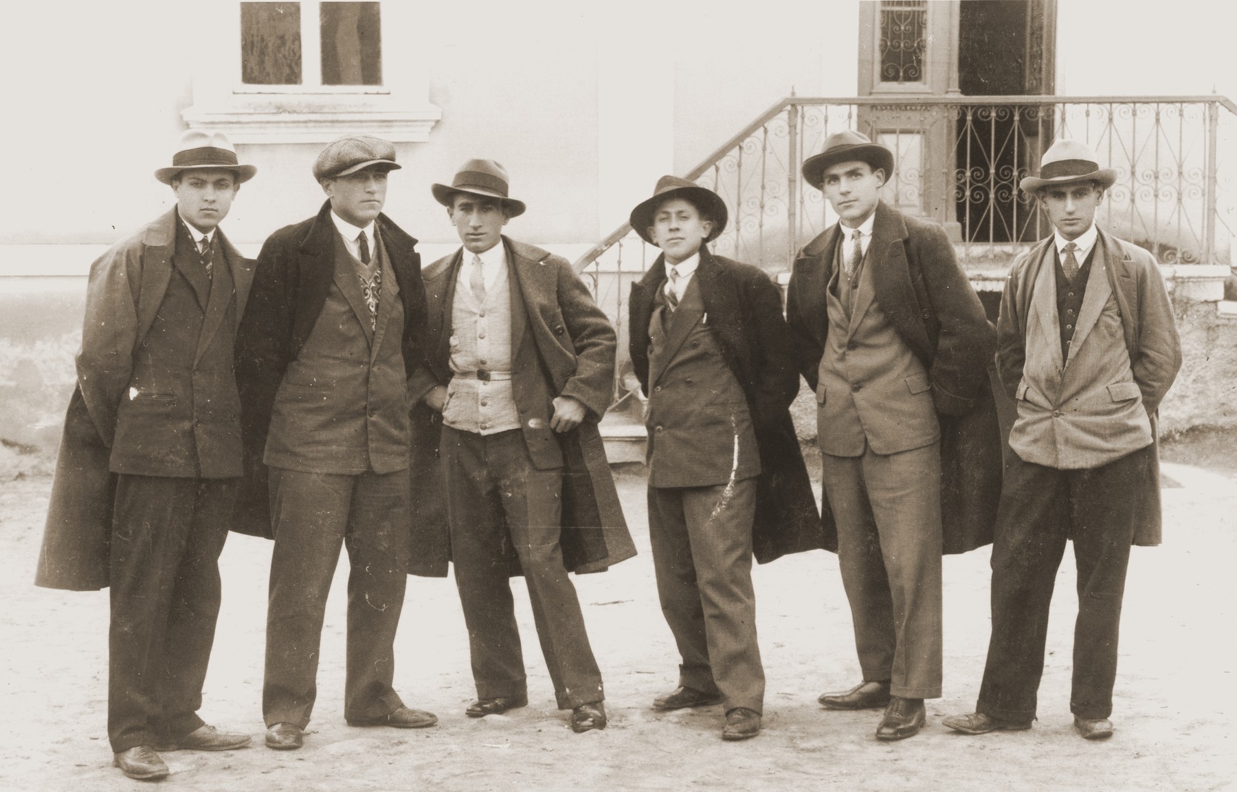 A group of young Jewish men in jackets and ties pose outside a building in Bitola, Macedonia.