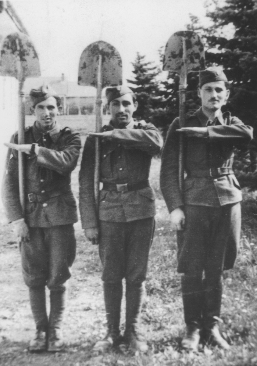 Three members of the 6th Labor Battalion stand at attention with their shovels.