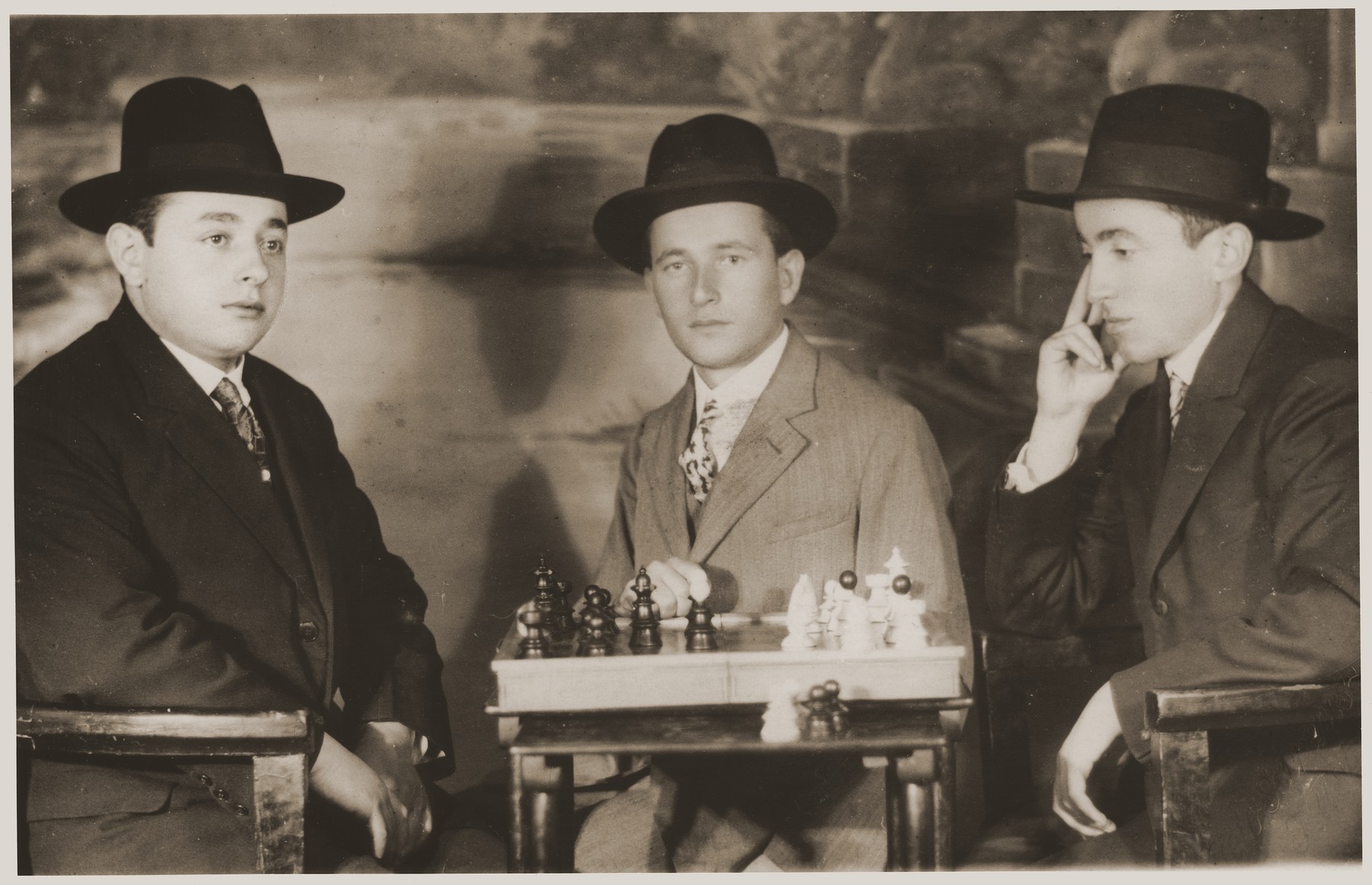 Yeshiva students playing chess.  

Pictured from left to right are Meir Goldschild and his cousins, Moses and Yisroel Klein.
