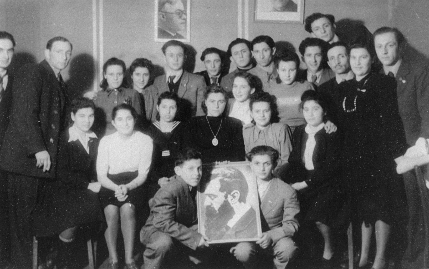 Members of Betar pose with a portrait of Theodor Herzl in the Schlachtensee displaced persons camp.  

Pictured are the Zycer brothers, Icka Lewin, Mishka Gleiberman, Yurek Snyder, Leizer Snyder, and Murka Bimbad.