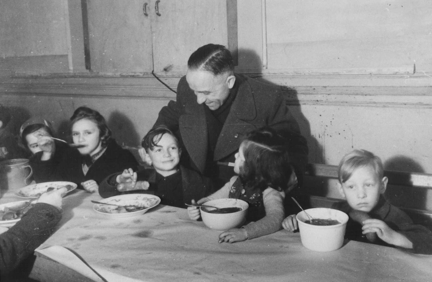 Carl Busch (standing) meets with DP children eating lunch in in the Jewish (Deutsche Juedische Jugend) school at the Berlin Chaplains' Center.