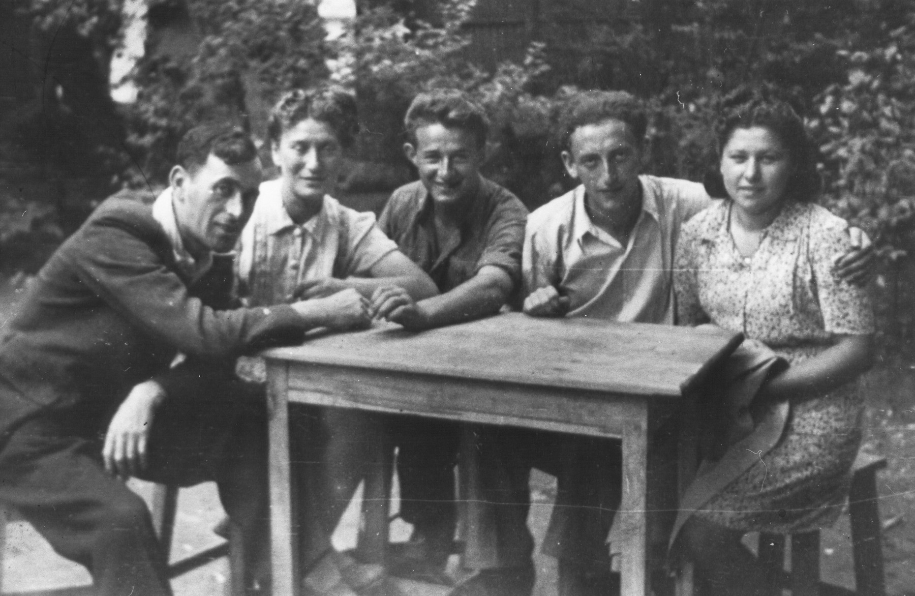 Members of the Nekama group gathered around a table during their stay in Bucharest.

Among those pictured are Baruch Goldstein (left) and Welvel Rabinovich (second from the right).