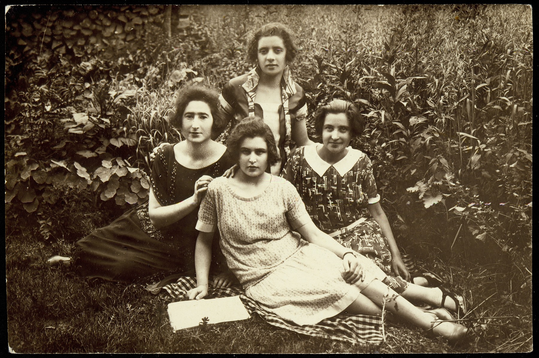 Four friends sit in a garden in Vilna.  

Sitting at the far left is Liebke Moszczenik Kabacznik.  Behind her is Marsha Kanichowski Yurkanski.  Sitting in the front is Shoshana (Shoshke) Wine. 

Liebke Kabacznik was murdered by members of the Polish Home Army in February 1944.  Shoshana (Shoshke) Wine was killed by a Russian partisan.  Marsha Yurkanski survived the war.