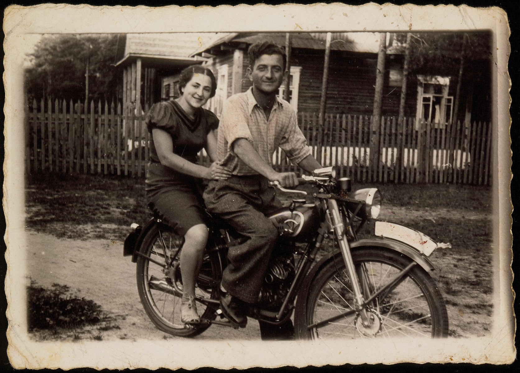 Shabbtai (Shepske) Sonenson takes one of the shtetl's Hebrew teachers for a ride on his new motorcycle.