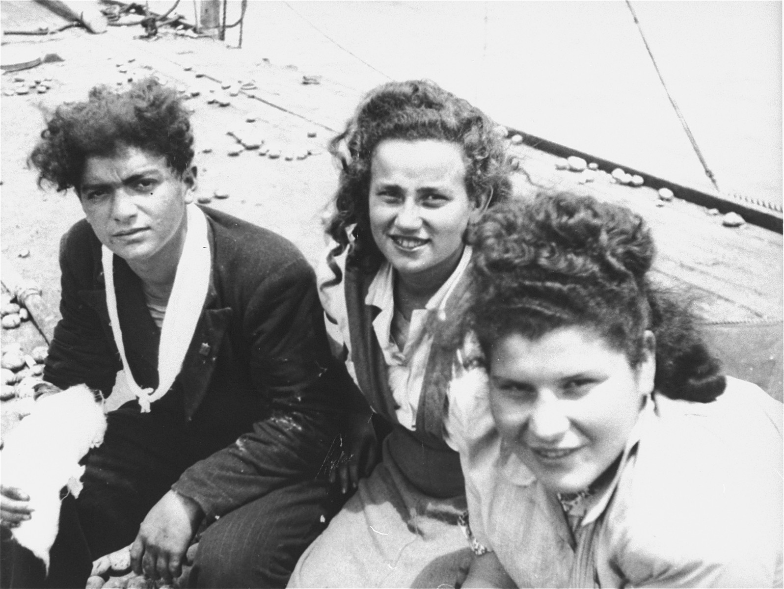 Three Jewish passengers, one of whom has been wounded, sit on the deck of the Exodus 1947.  Potatoes and other debris, used in the struggle with the British, lie on the deck behind them.