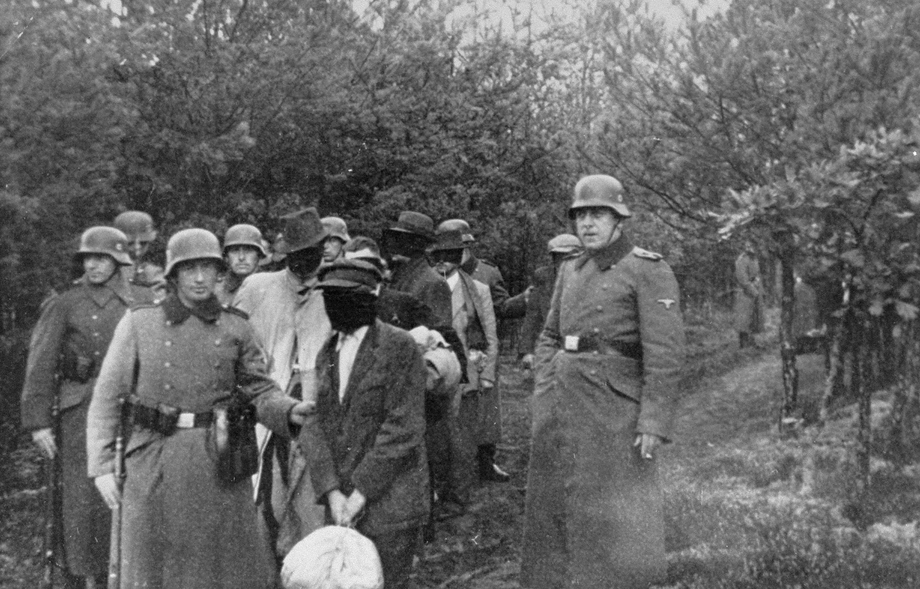 SS personnel lead a group of blindfolded Polish prisoners to an execution site in the Palmiry forest near Warsaw.  These civilians had been held in the Palmiry and Mokotow prisons in Warsaw.