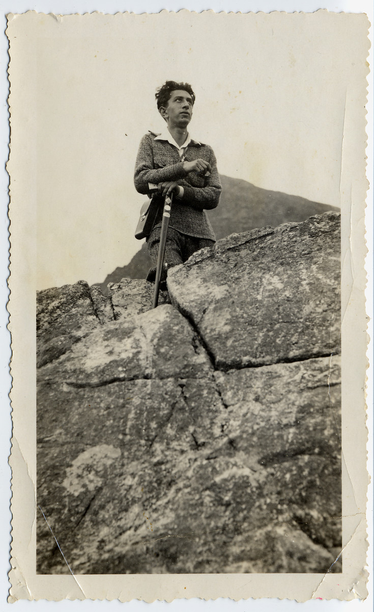 Avraham (Romek) Bialer poses on a cliff while hiking in Palestine.