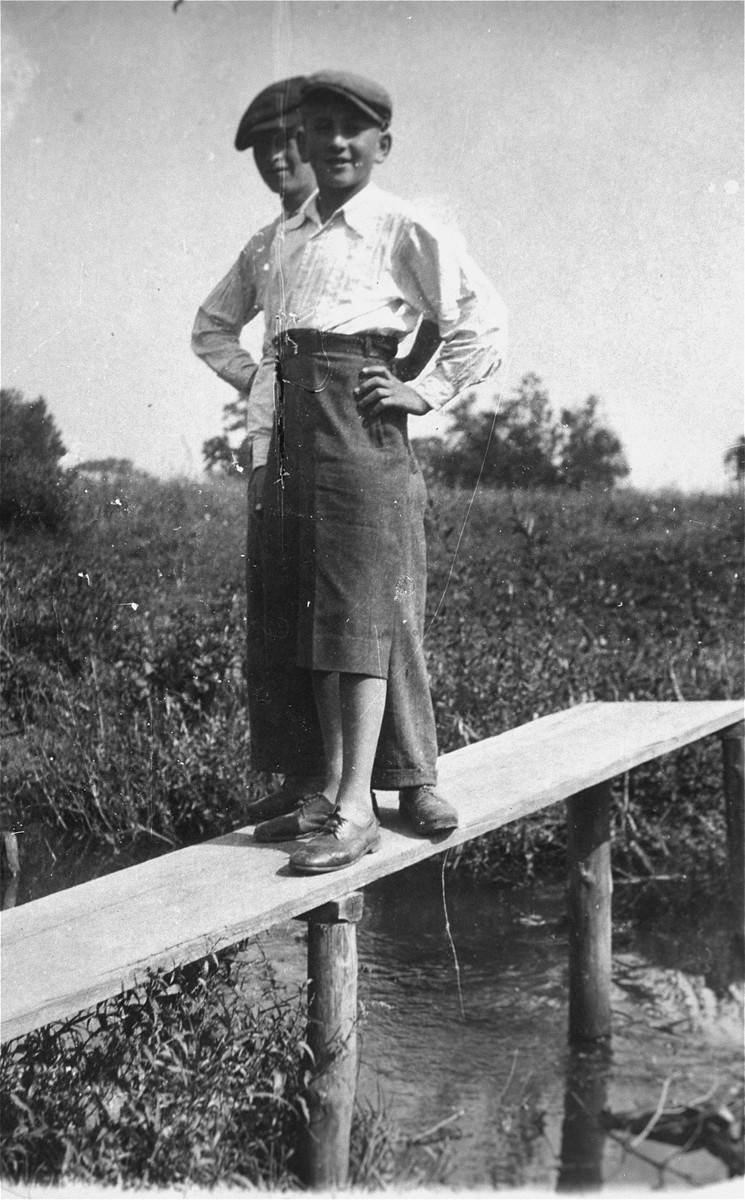 Two Jewish youth pose on a wooden beam in the Kolbuszowa ghetto.

Pictured is Manius Notowicz and a friend.